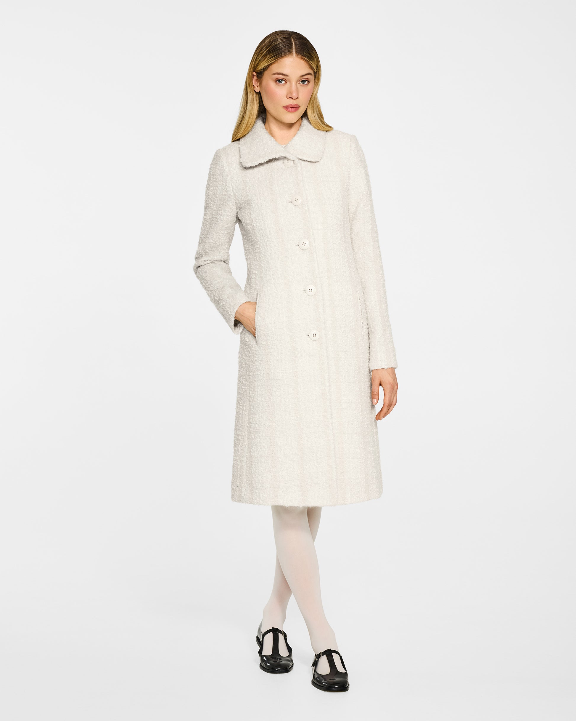 Front view of model wearing a Sentaler ivory glittered A-line coat made of tweed suri alpaca wool, worn buttoned.