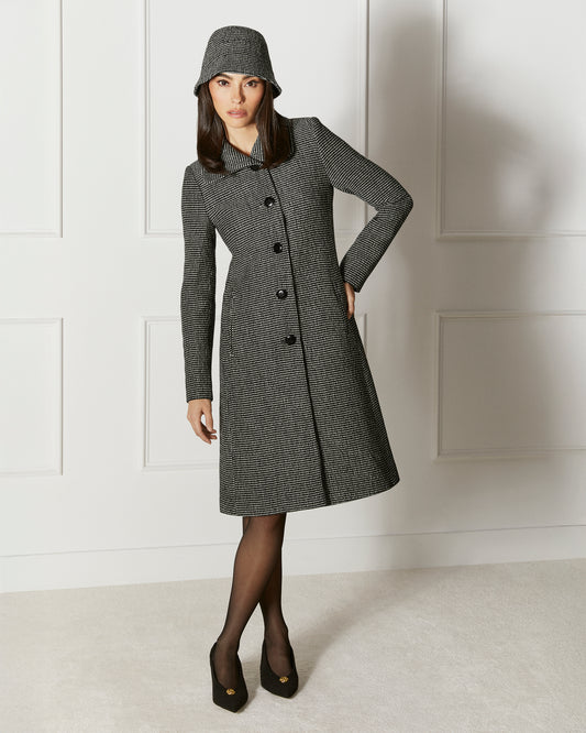 Front view of model wearing a Sentaler black, gold and ivory A-line coat made of tweed suri alpaca wool, worn buttoned.