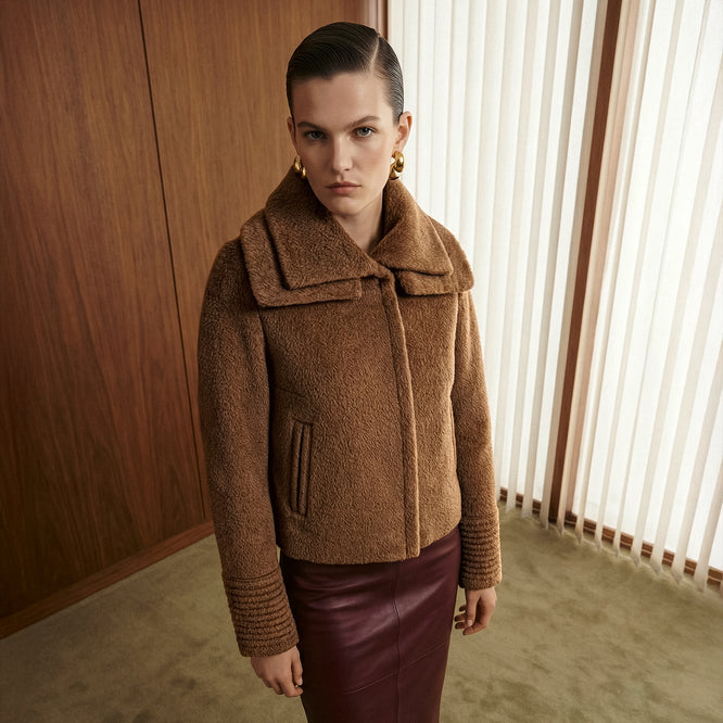 Front view of model wearing a Sentaler dark camel moto jacket made of bouclé alpaca wool, with a double collar, worn buttoned.