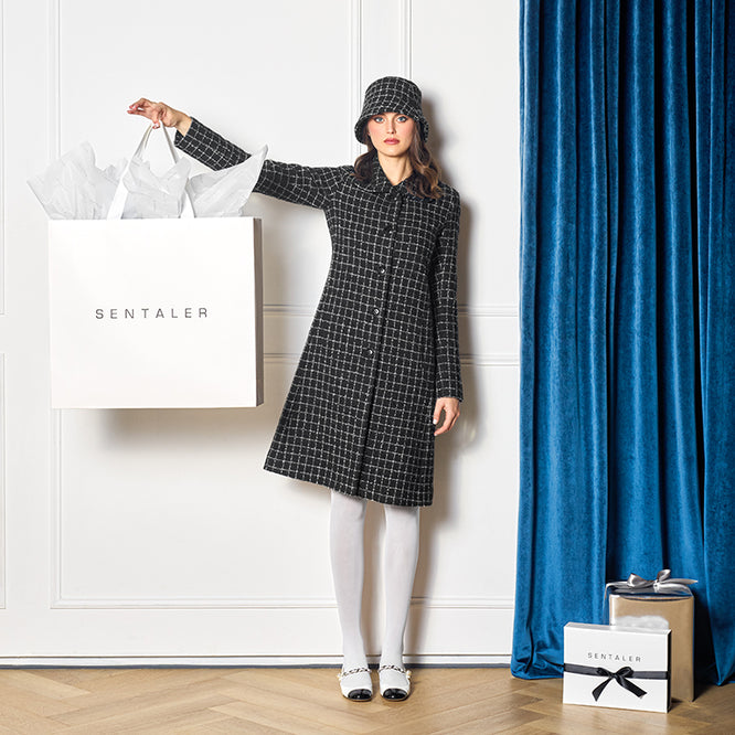 Sentaler Tweed Alpaca A-line Black Check Coat in Tweed Suri Alpaca wool. Seen from front on female model holding SENTALER gift bag.