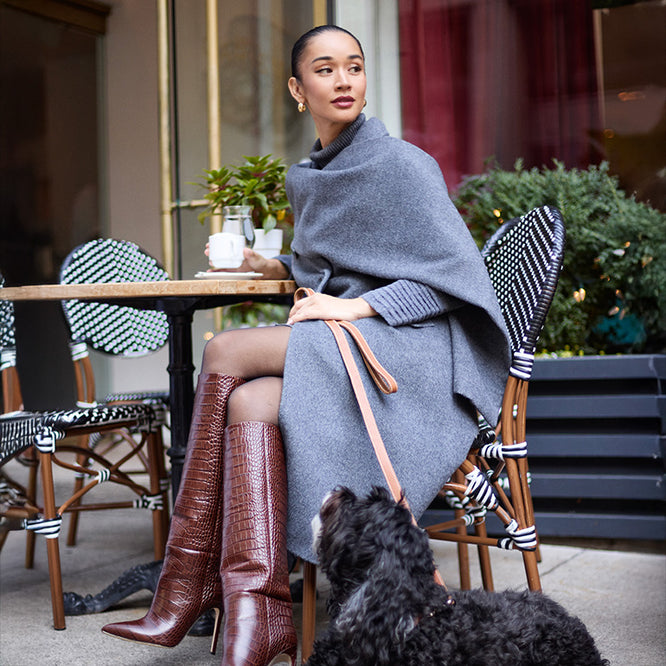Side view of model wearing a Sentaler grey mélange double breasted coat made of baby alpaca wool with a notched collar, worn with fabric scarf, buttoned & belted.