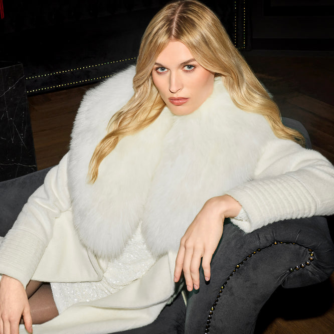 Front view of model wearing a Sentaler ivory maxi coat made of suri alpaca wool, with an alpaca shearling collar, seen belted.