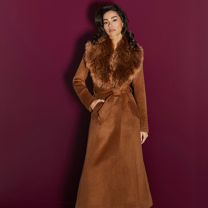 Front view of model wearing a  Sentaler caramel maxi coat made of suri alpaca wool, with an alpaca shearling collar, seen belted.