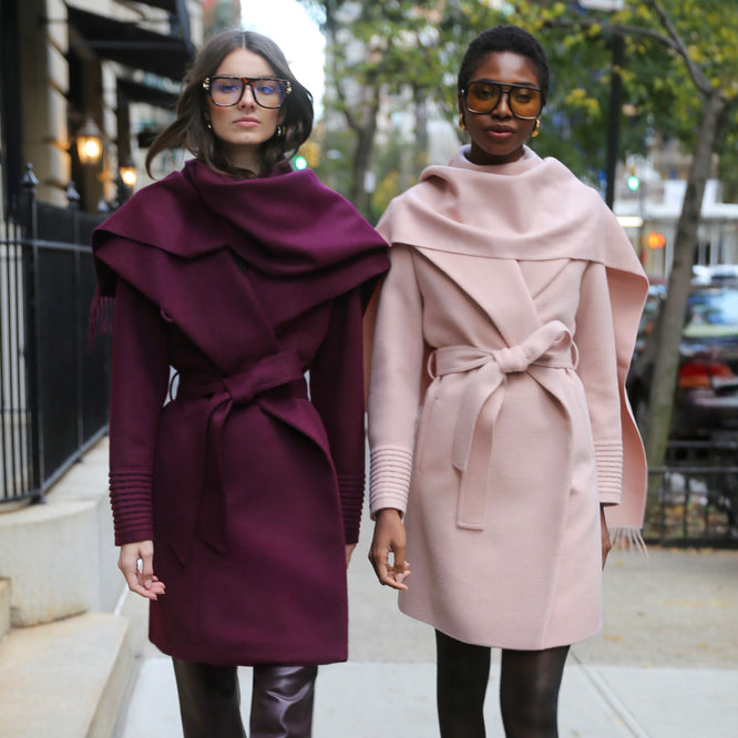 Front view of models wearing a Sentaler mid length cherry lacquer coat & blush pink coat, made of baby alpaca wool, worn belted.