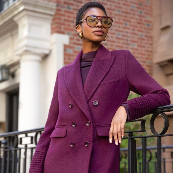 Front close up view of model wearing a Sentaler cherry lacquer double breasted maxi coat made of baby alpaca wool, with a peak collar, worn buttoned.