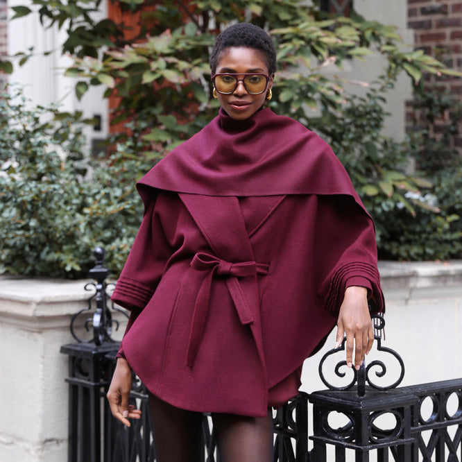 Front view of model wearing Sentaler cherry lacquer cape made of baby alpaca wool, with a shawl collar, worn belted with matching cherry lacquer classic baby alpaca scarf.
