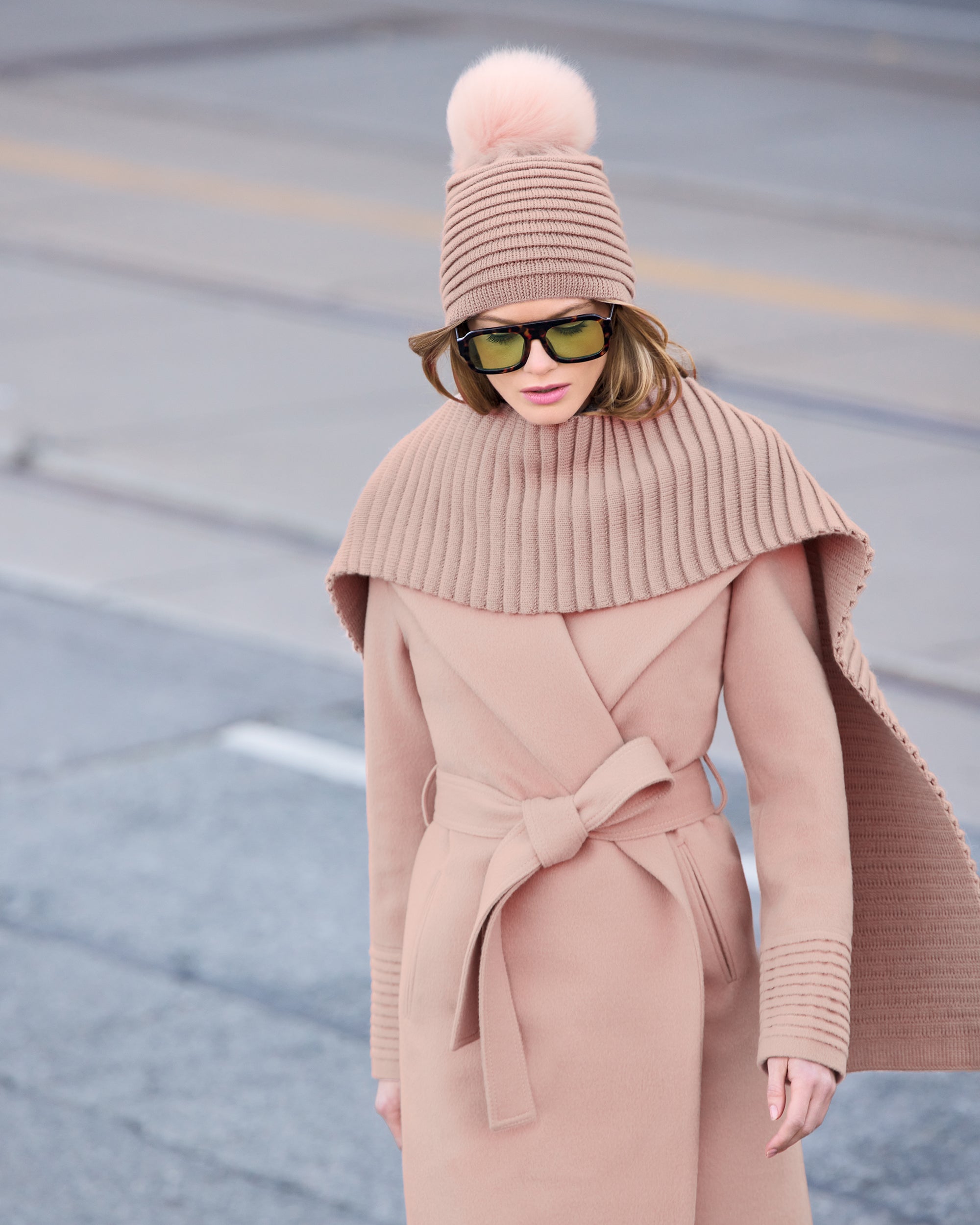 Front close up view of model wearing a Sentaler mid length blush pink coat made of baby alpaca wool, with a shawl collar, worn belted.