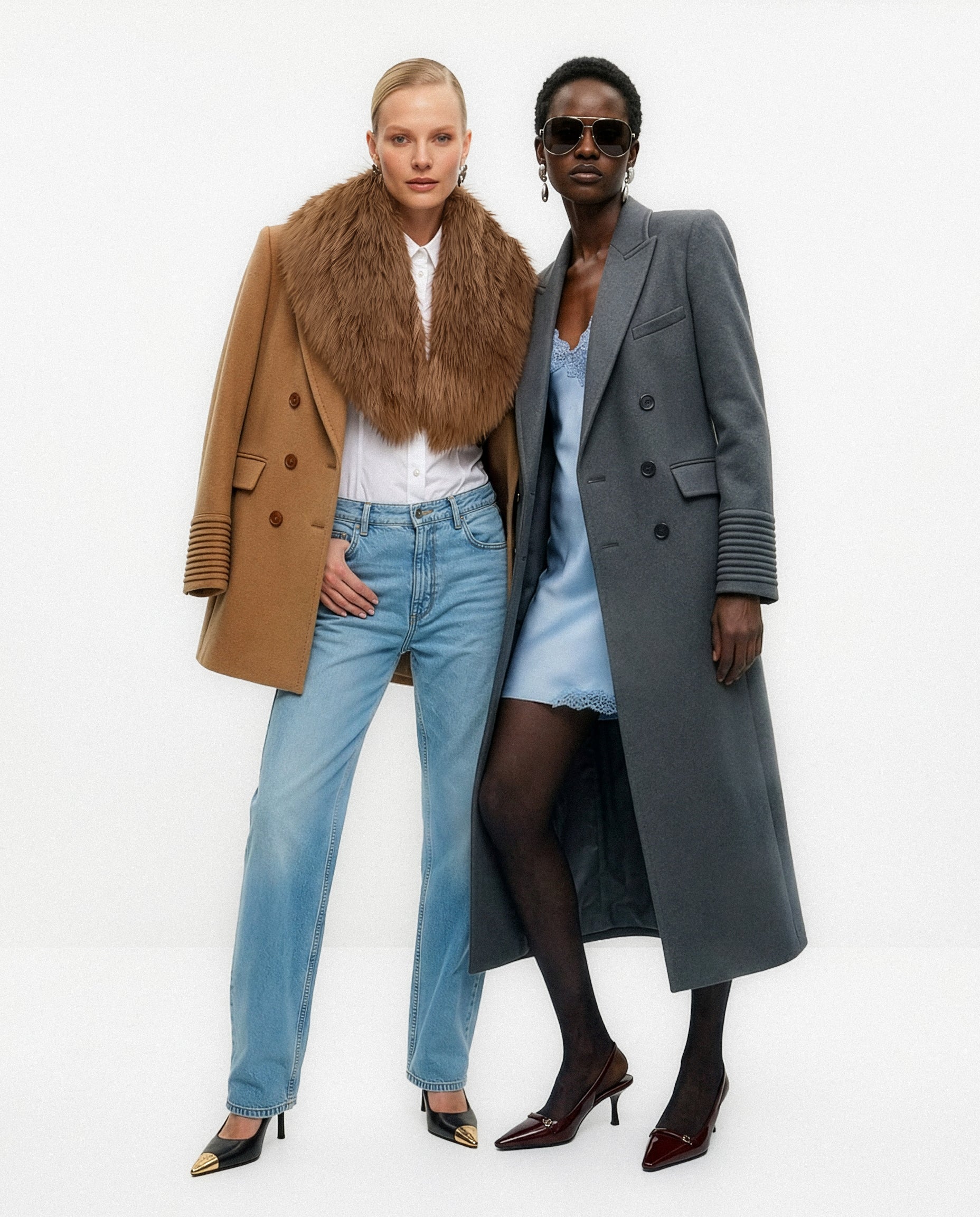 Front view of models wearing a Sentaler dark camel topcoat made of baby alpaca wool, with a peak collar, worn unbuttoned with shearling collar, and a Sentaler graphite double breasted maxi coat made of baby alpaca wool, with a peak collar, worn unbuttoned.