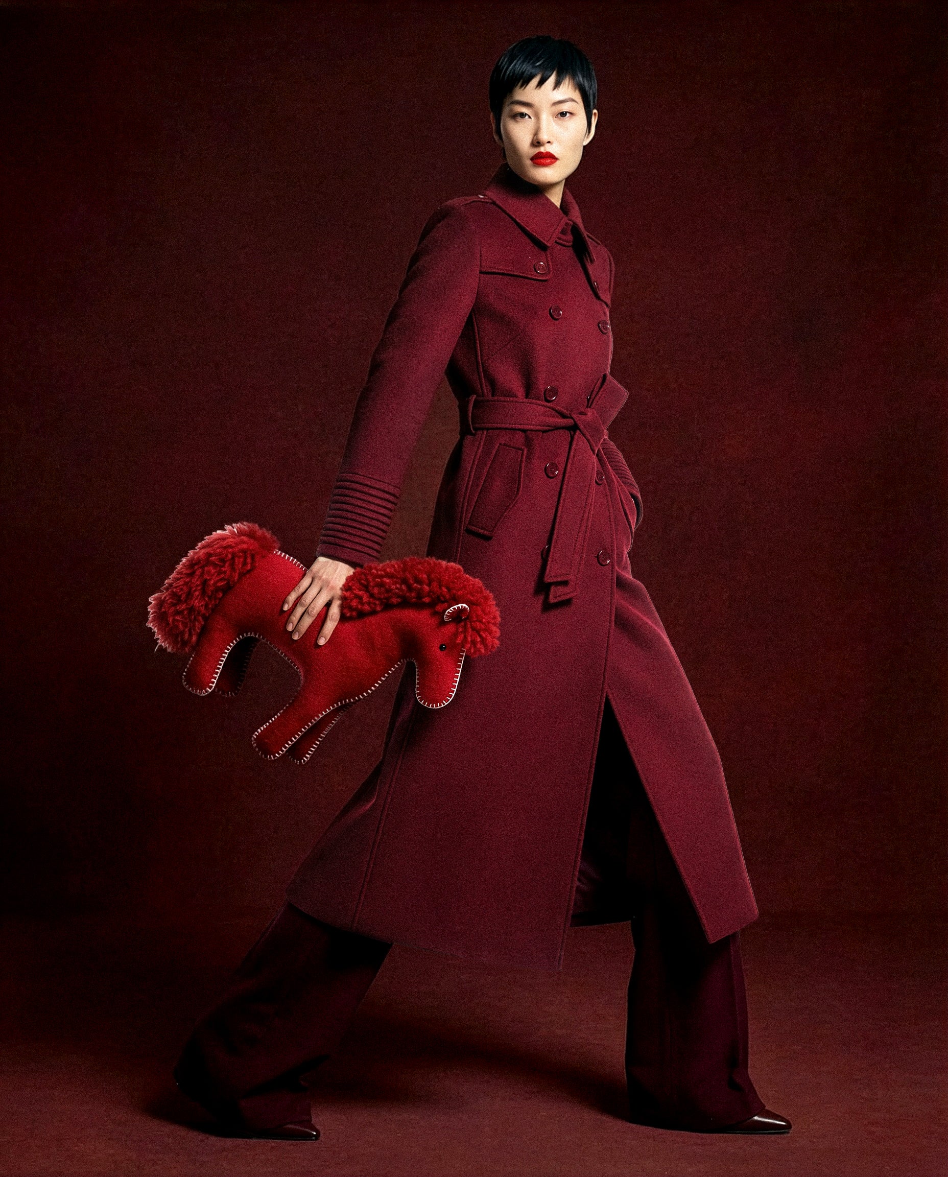 Front view of model in Sentaler maxi black trench coat made of baby alpaca wool with shearling collar, buttoned and belted.