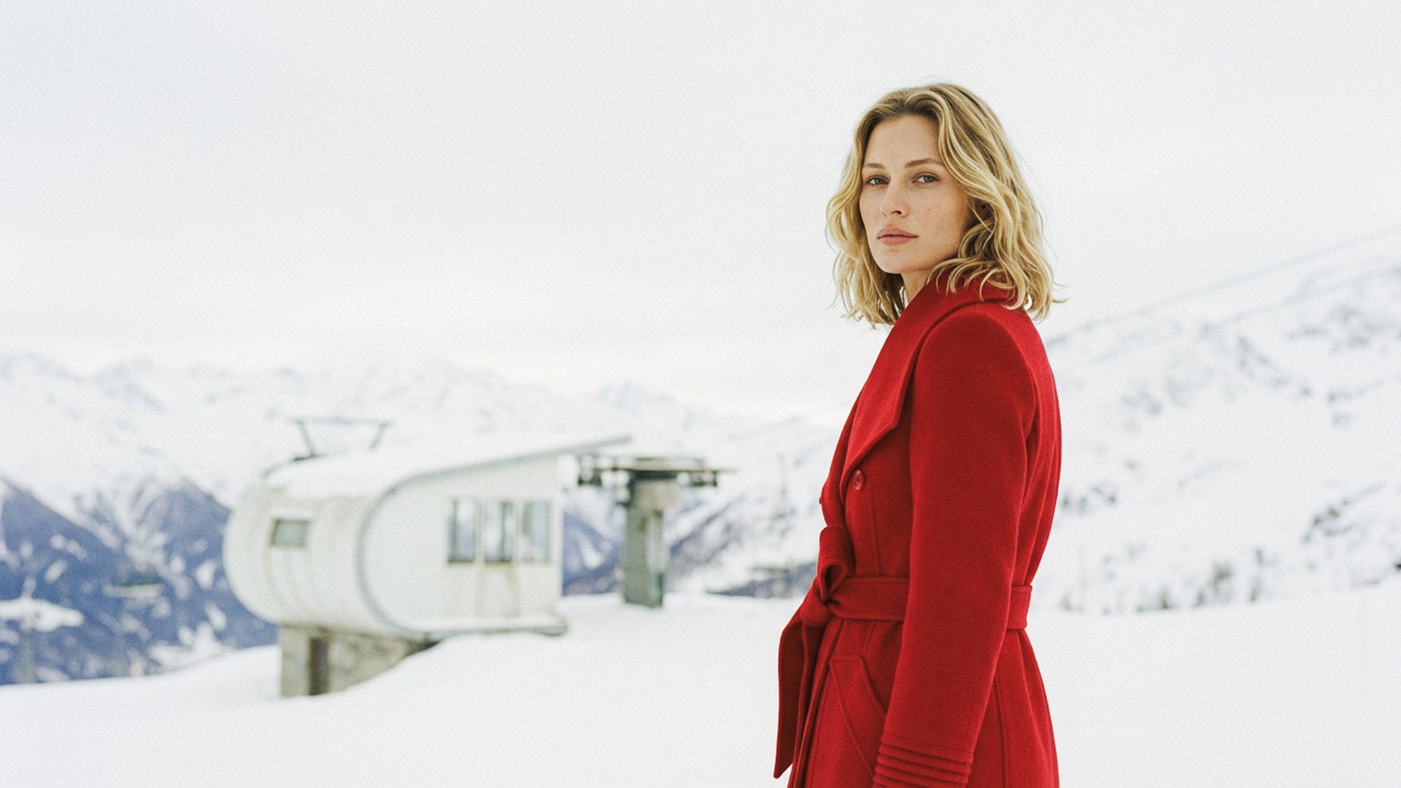 Side view of model wearing a Sentaler scarlet red long wrap coat made of baby alpaca wool, with a wide collar, worn belted.