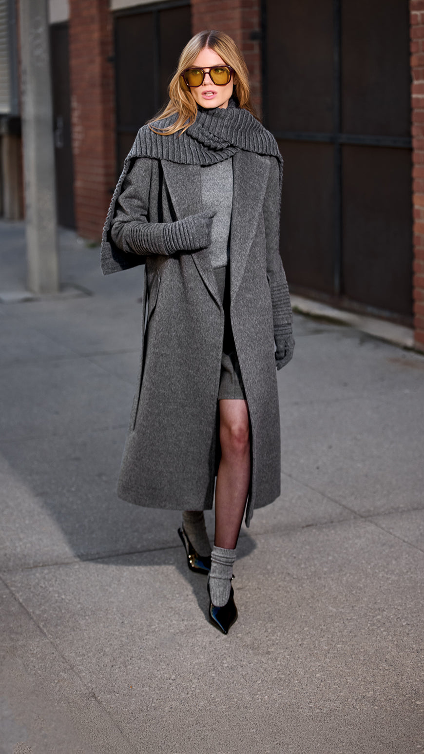 Front view of model wearing Sentaler's signature grey mélange ribbed hat, scarf, and gloves, paired with a matching grey mélange coat.