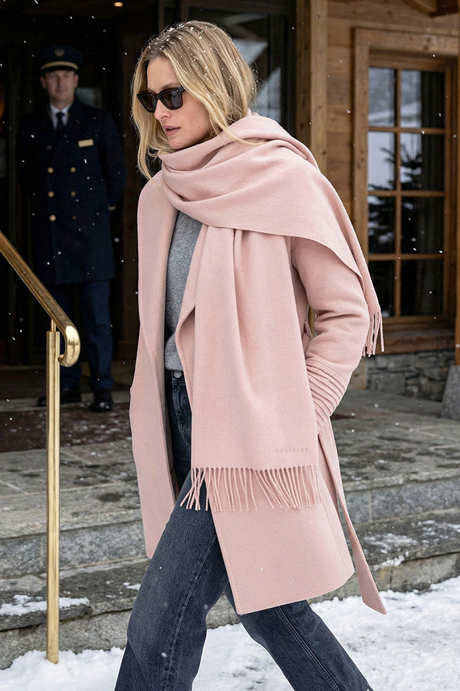 Front view of model wearing a Sentaler mid length blush pink coat made of baby alpaca wool, with a shawl collar, worn belted.