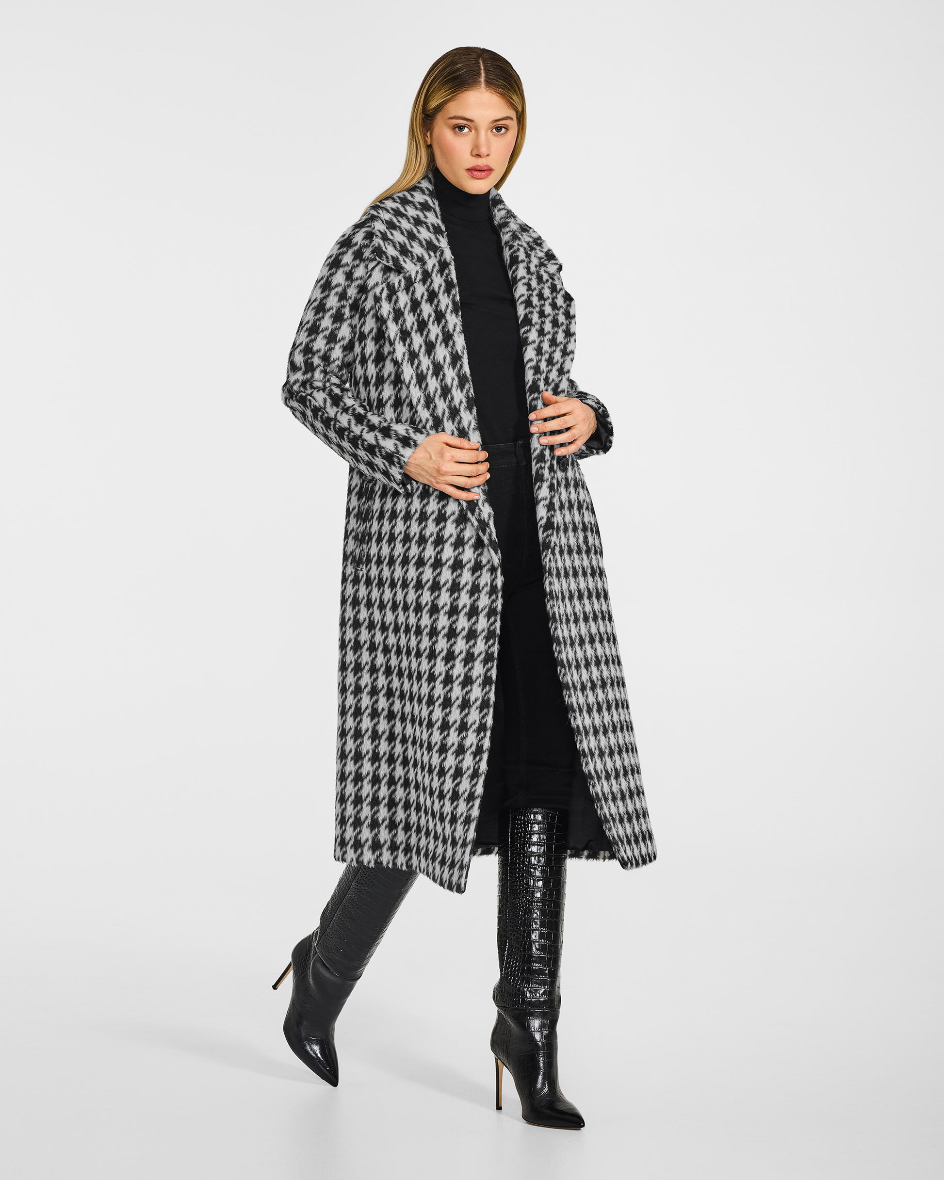 Side view of model wearing a Sentaler black and white houndstooth coat made of suri alpaca wool, with raglan sleeves, worn open.