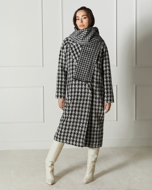 Front view of model wearing a Sentaler black and white houndstooth coat made of suri alpaca wool, with raglan sleeves, worn buttoned.