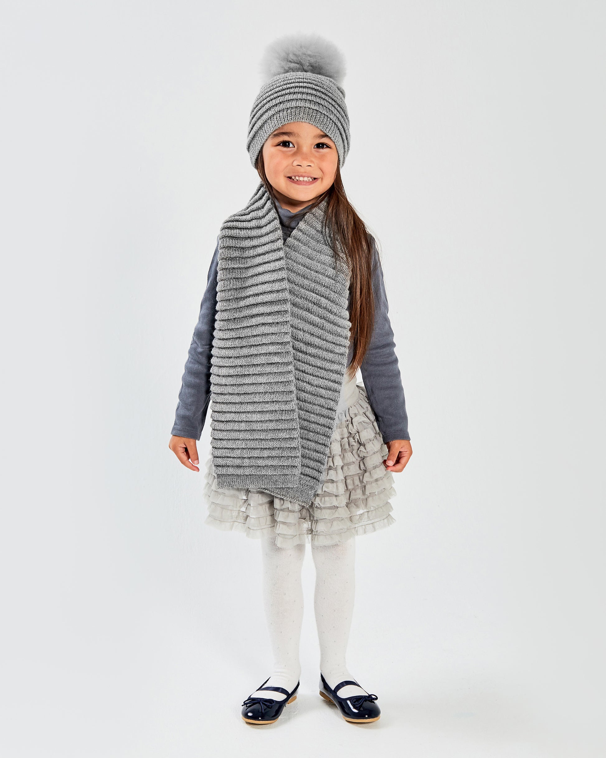 Sentaler Kids Ribbed Grey Scarf & Pompon Hat (1-5 Years) in Baby Alpaca yarn. Seen from front on girl model.