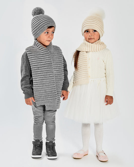 Sentaler Kids Ribbed Ivory Scarf & Pompon Hat (1-5 Years) in Baby Alpaca yarn. Seen from front on girl model.