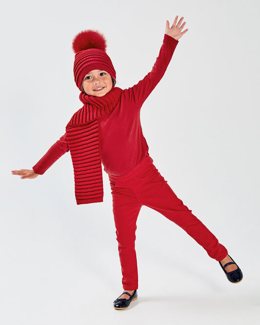 Sentaler Kids Ribbed Red Hat with Fur Pompon (1-5 Years) and Kids Ribbed Red Scarf (1-5 Years) in Baby Alpaca yarn. Seen from front on girl model.