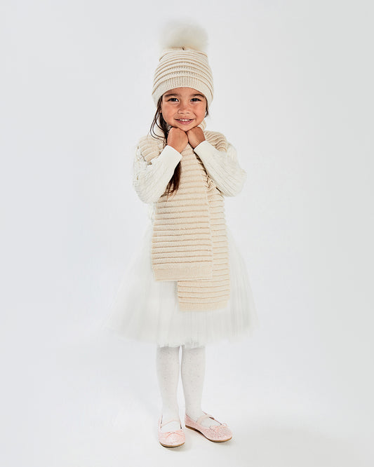 Sentaler Kids Ribbed Ivory Hat with Fur Pompon (4-5 Years) and Kids Ribbed Ivory Scarf (4-5 Years) in Baby Alpaca yarn. Seen from front on girl model.