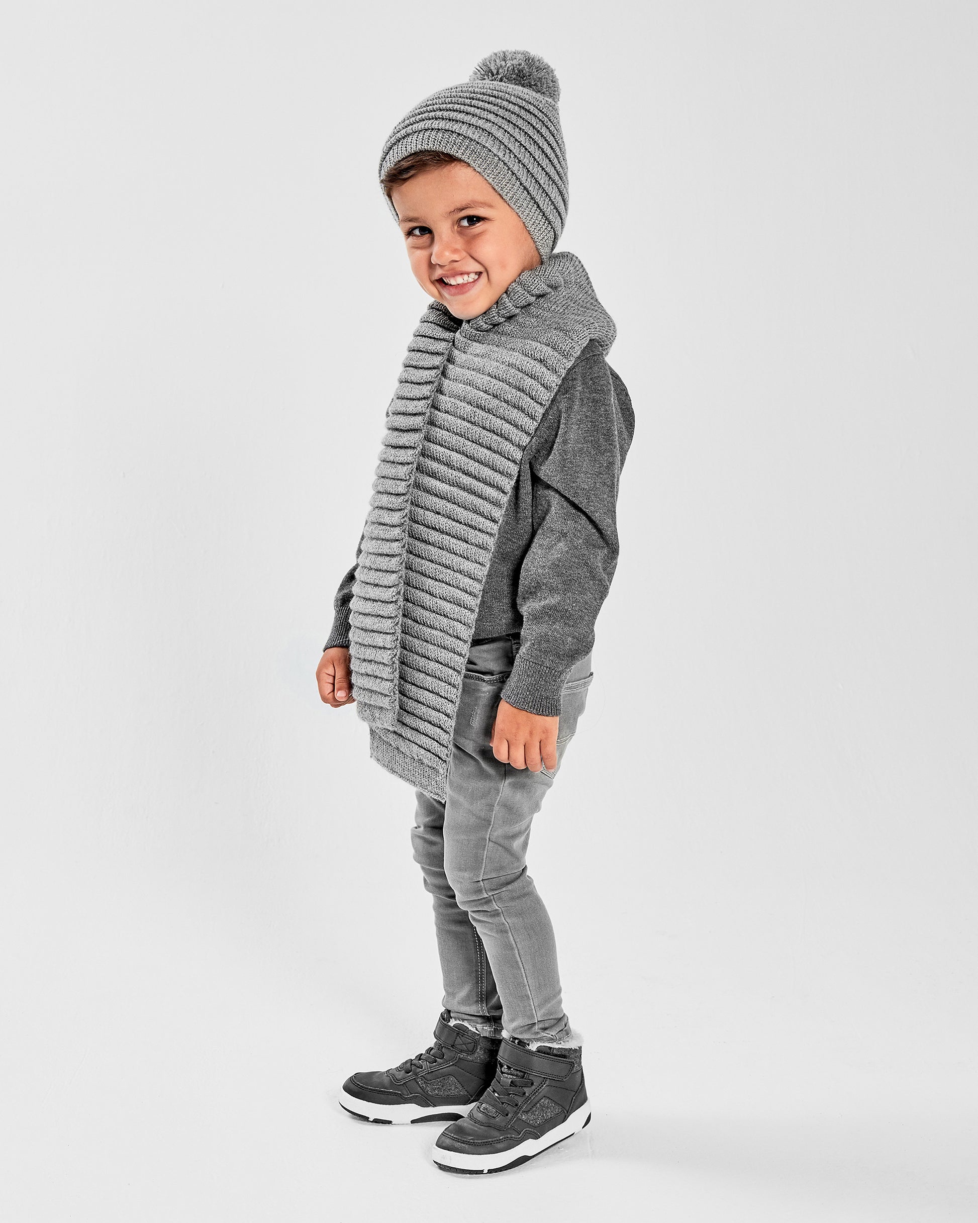 Sentaler Kids Ribbed Grey Hat with Knit Pompon (1-5 Years) and Kids Ribbed Grey Scarf (1-5 Years) in Baby Alpaca yarn. Seen from side on boy model.