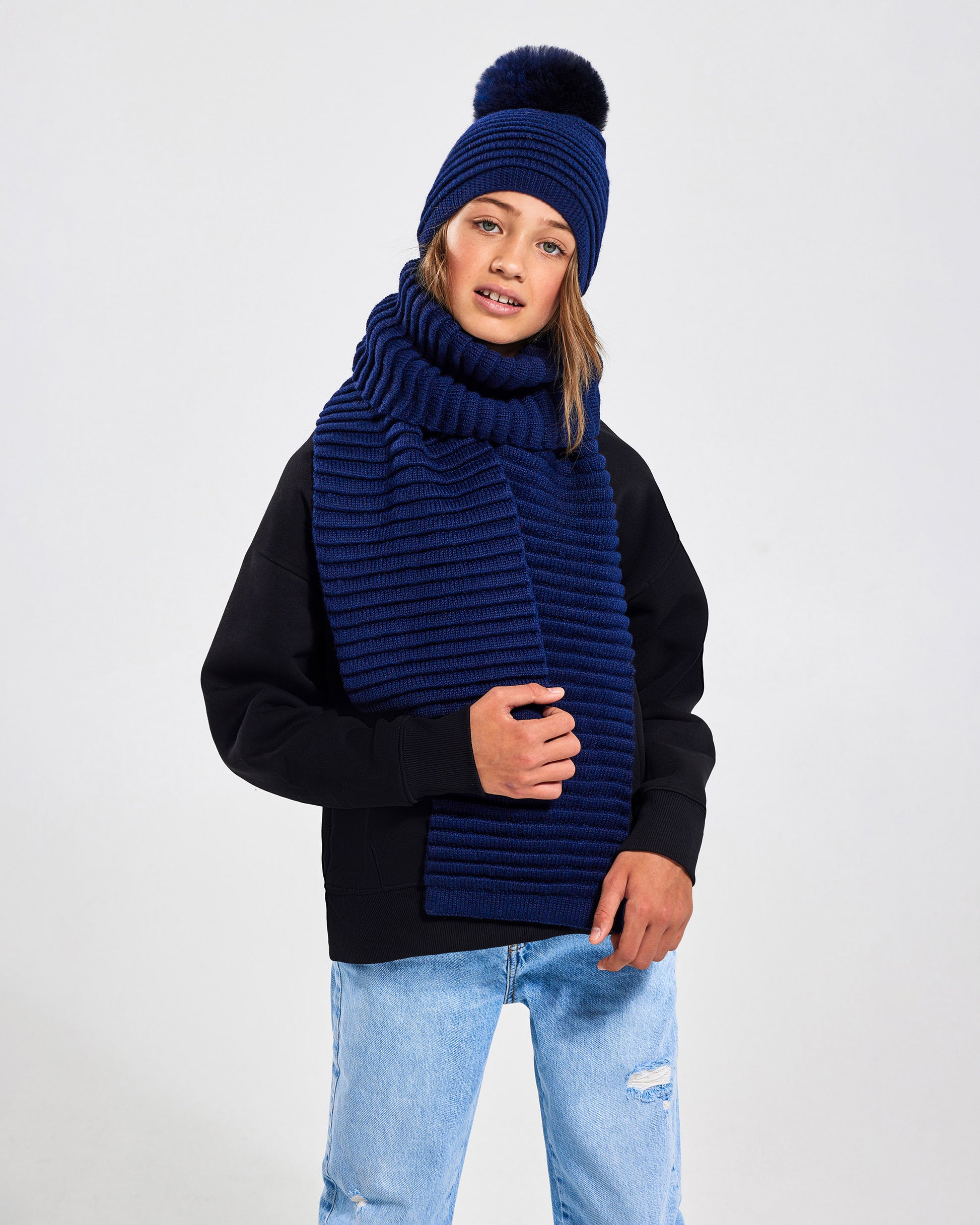 Sentaler Kids Ribbed Navy Hat with Fur Pompon (6-14 Years) in Baby Alpaca yarn. Seen from front close up on girl model.
