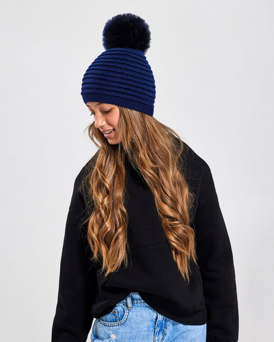 Sentaler Kids Ribbed Navy Hat with Fur Pompon (6-14 Years) in Baby Alpaca yarn. Seen from front close up on girl model.
