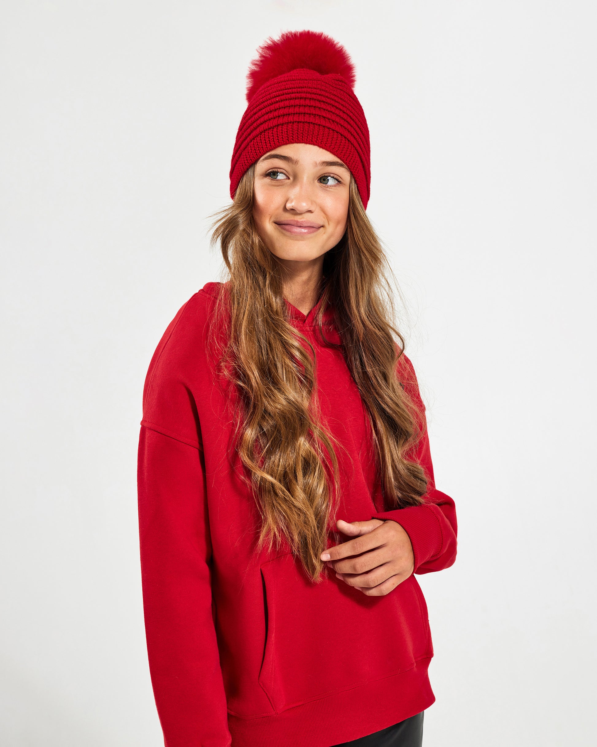 Sentaler Kids Ribbed Red Hat with Fur Pompon (6-14 Years) in Baby Alpaca yarn. Seen from side close up on girl model.