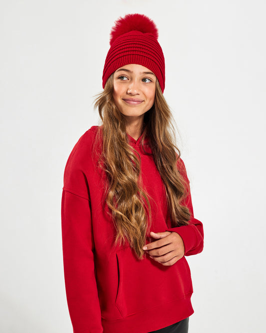 Sentaler Kids Ribbed Red Hat with Fur Pompon (6-14 Years) in Baby Alpaca yarn. Seen from side close up on girl model.