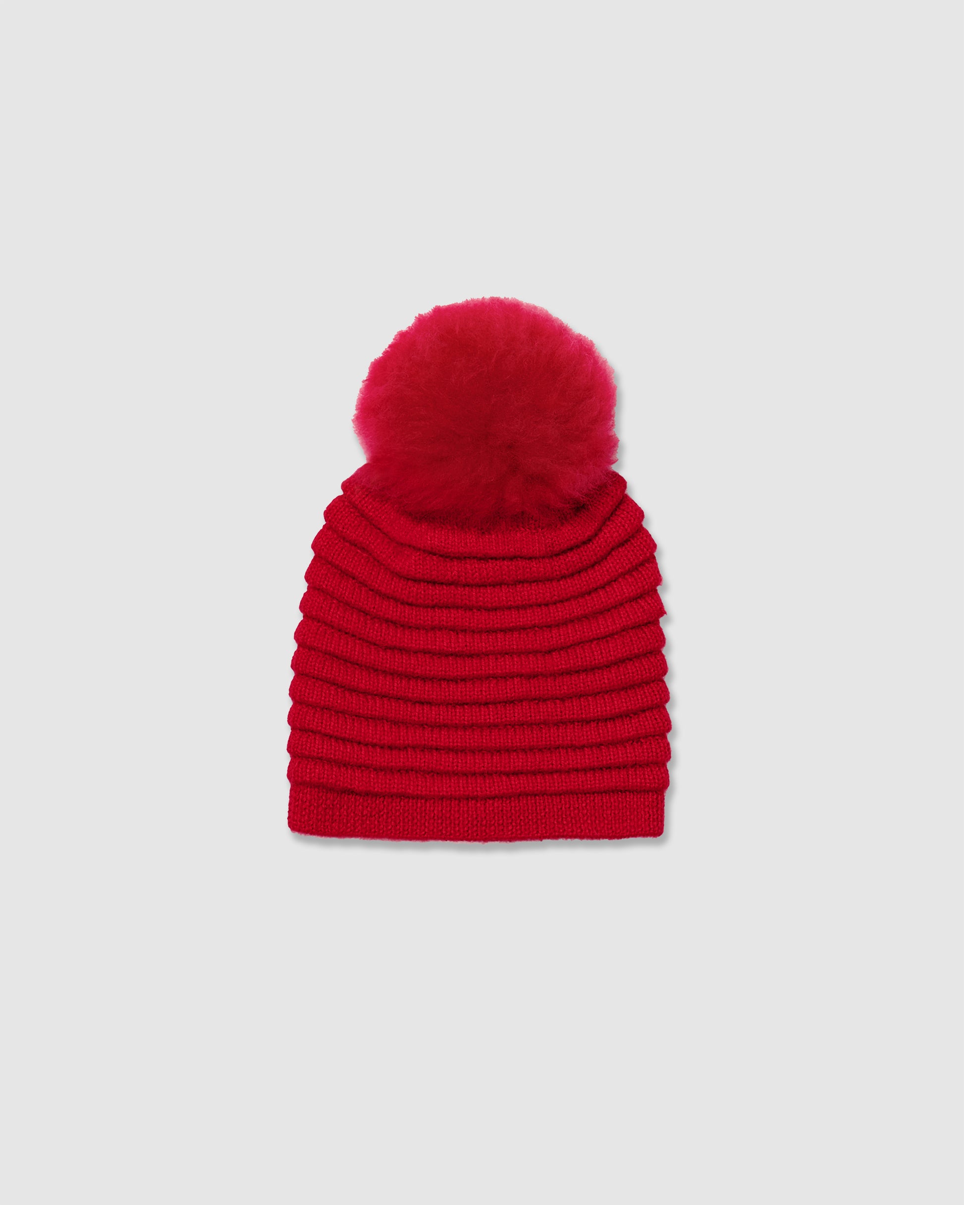 Sentaler kids (6-14 years) ribbed red winter hat made of Baby Alpaca fabric with oversized fur pompom, displayed on a white background.