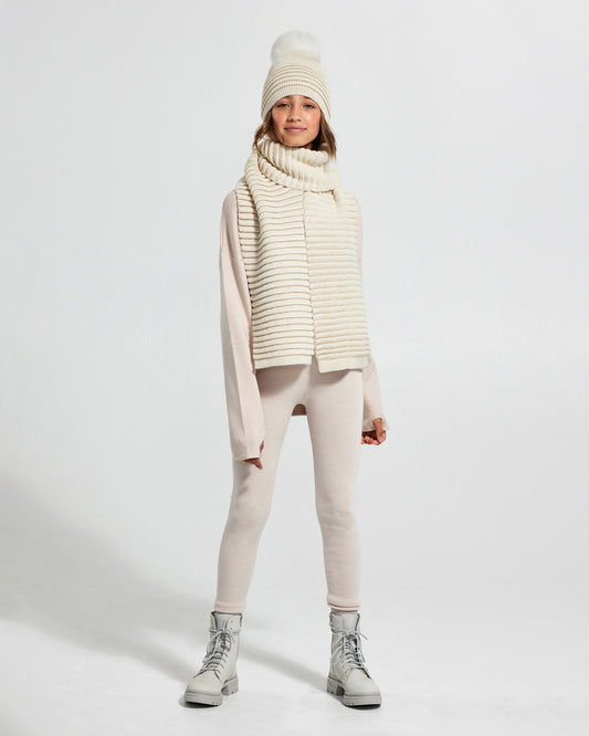 Sentaler Kids Ribbed IvoryScarf (6-14 Years) and Kids Ribbed Ivory Hat with Fur Pompon (6-14 Years) in Baby Alpaca yarn. Seen from front on girl model.