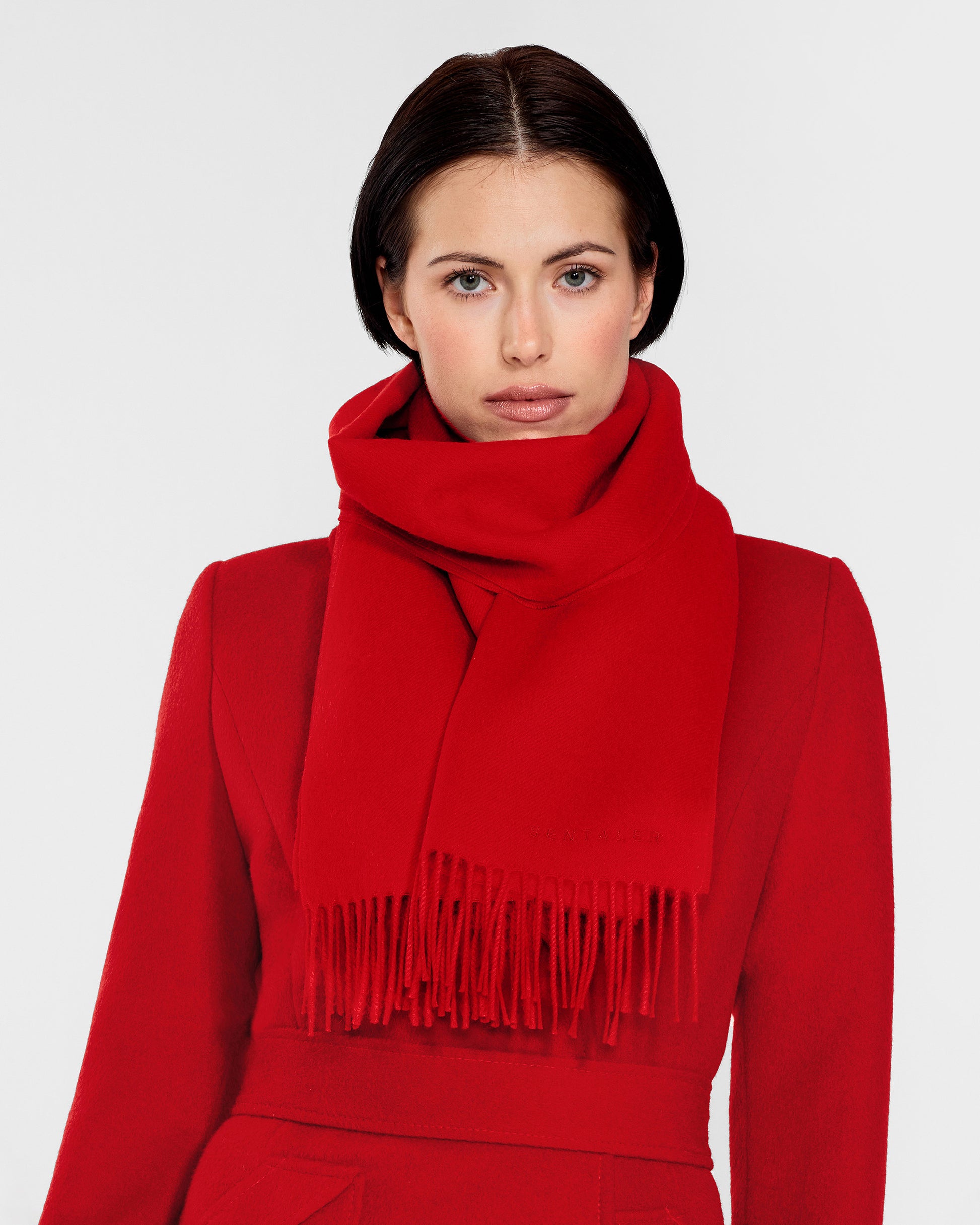 Front close up view of model wearing Sentaler's adult Red classic scarf, made of baby alpaca yarn. 