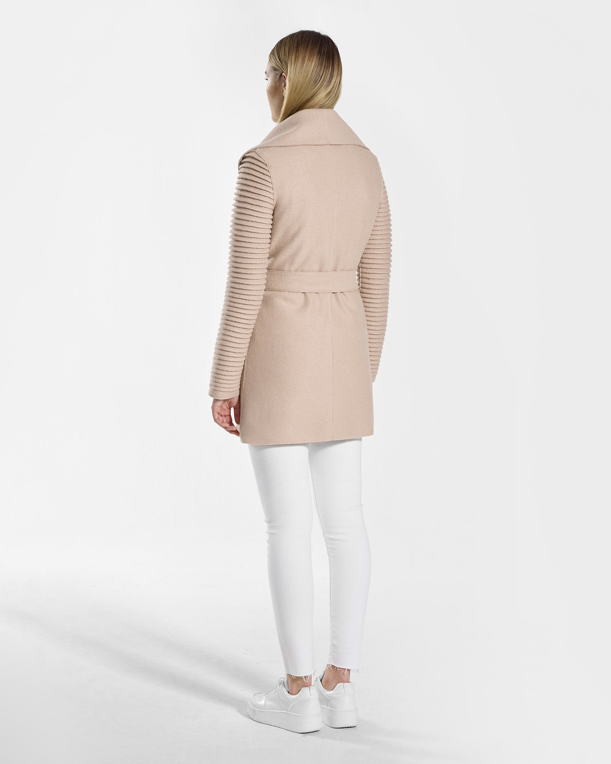 Back view of model wearing a Sentaler chamois beige wrap coat made of superfine alpaca wool, with ribbed sleeves, worn belted.