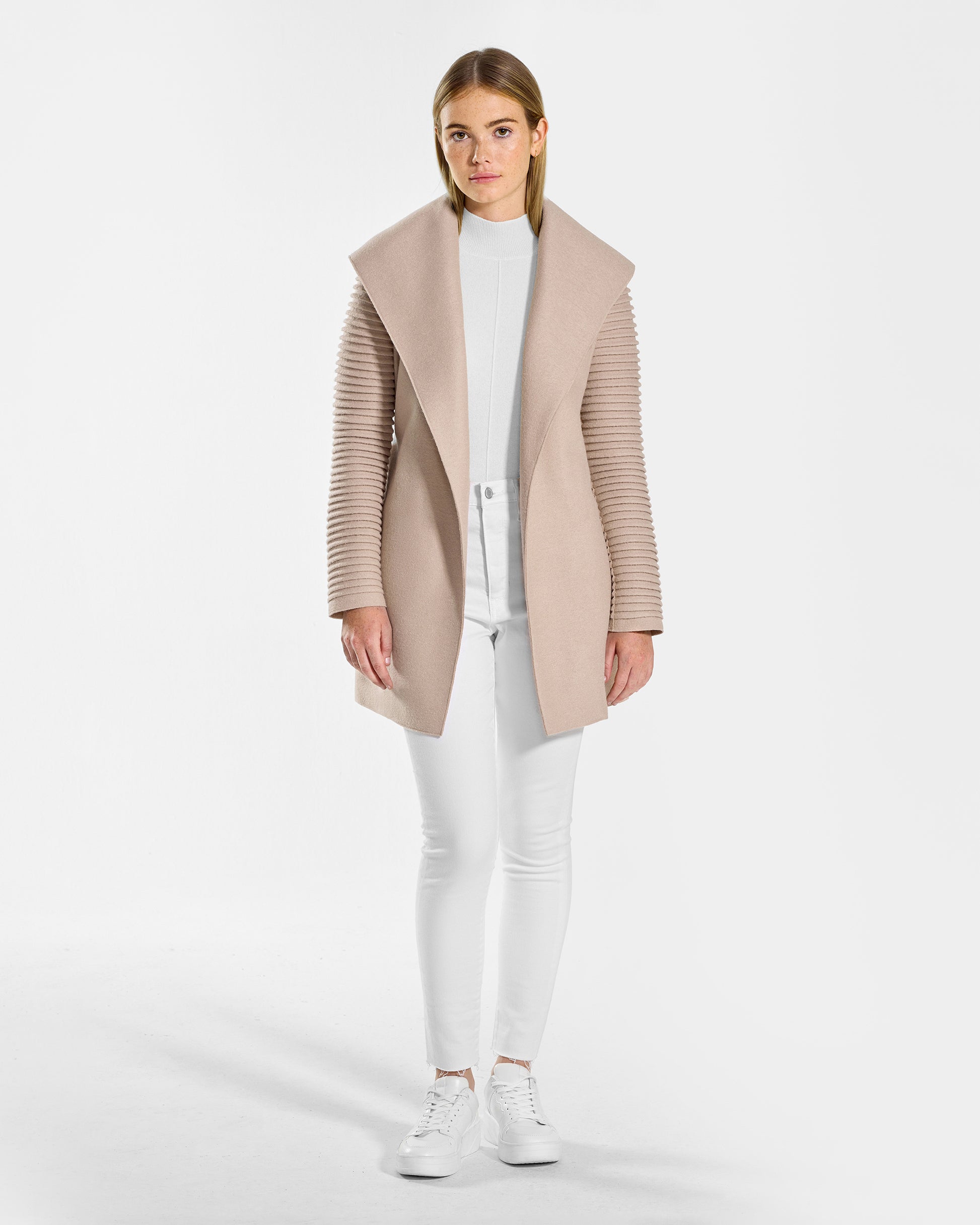 Front view of model wearing a Sentaler chamois beige wrap coat made of superfine alpaca wool, with ribbed sleeves, worn open.