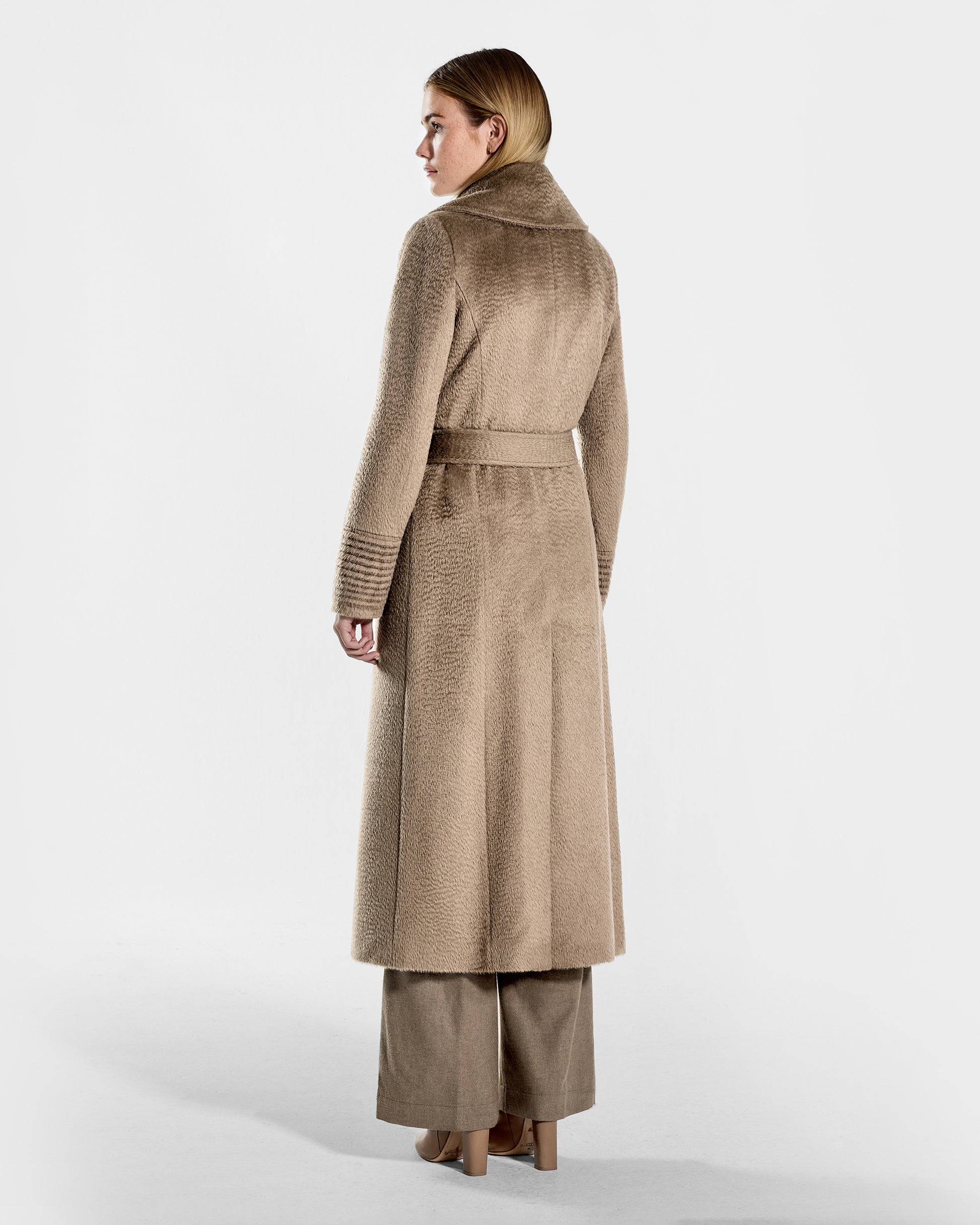 Back view of model wearing a SENTALER long hazelnut brown wrap coat made of suri alpaca wool, with a large notched collar, worn belted.
