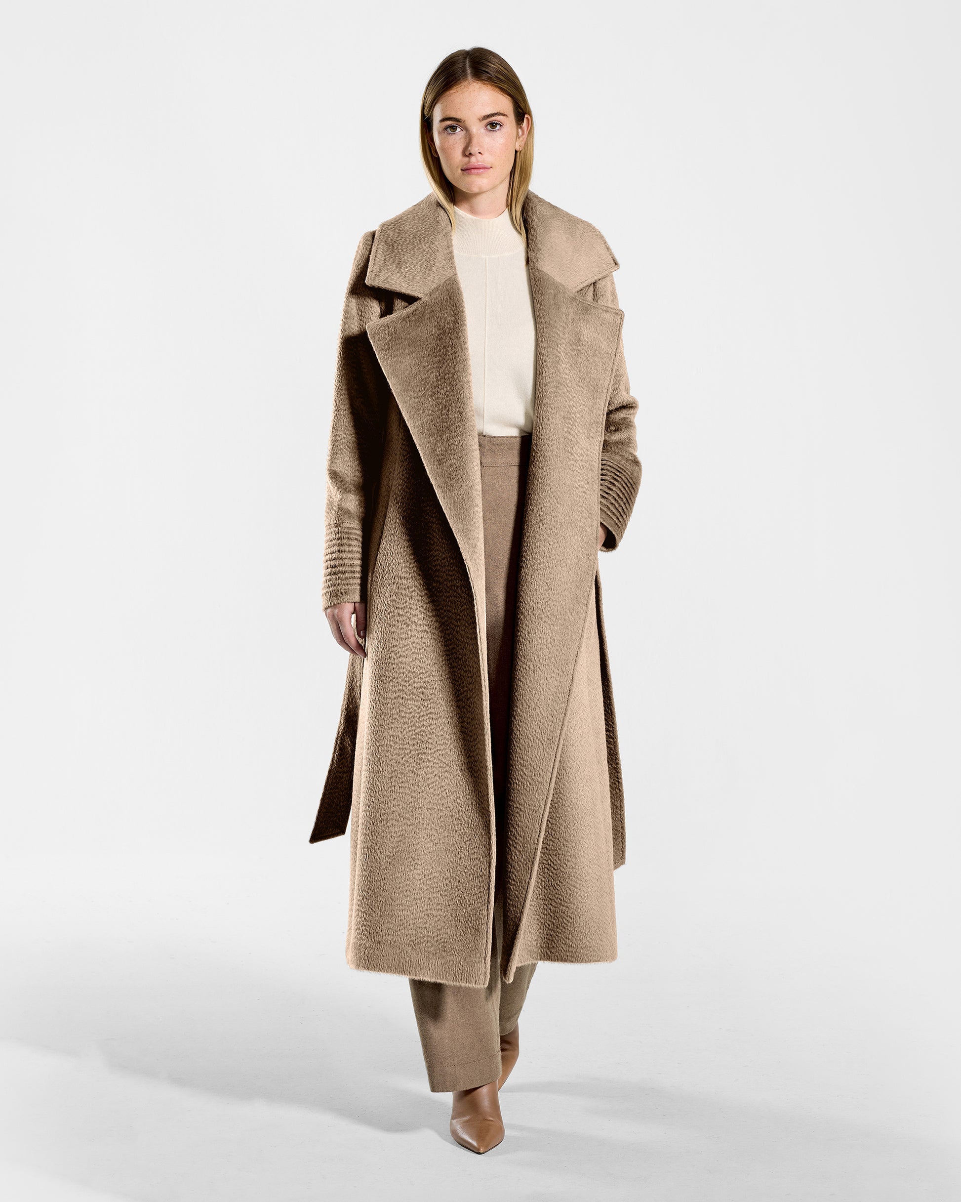 Front view of model wearing a SENTALER long hazelnut brown wrap coat made of suri alpaca wool, with a large notched collar, worn open.