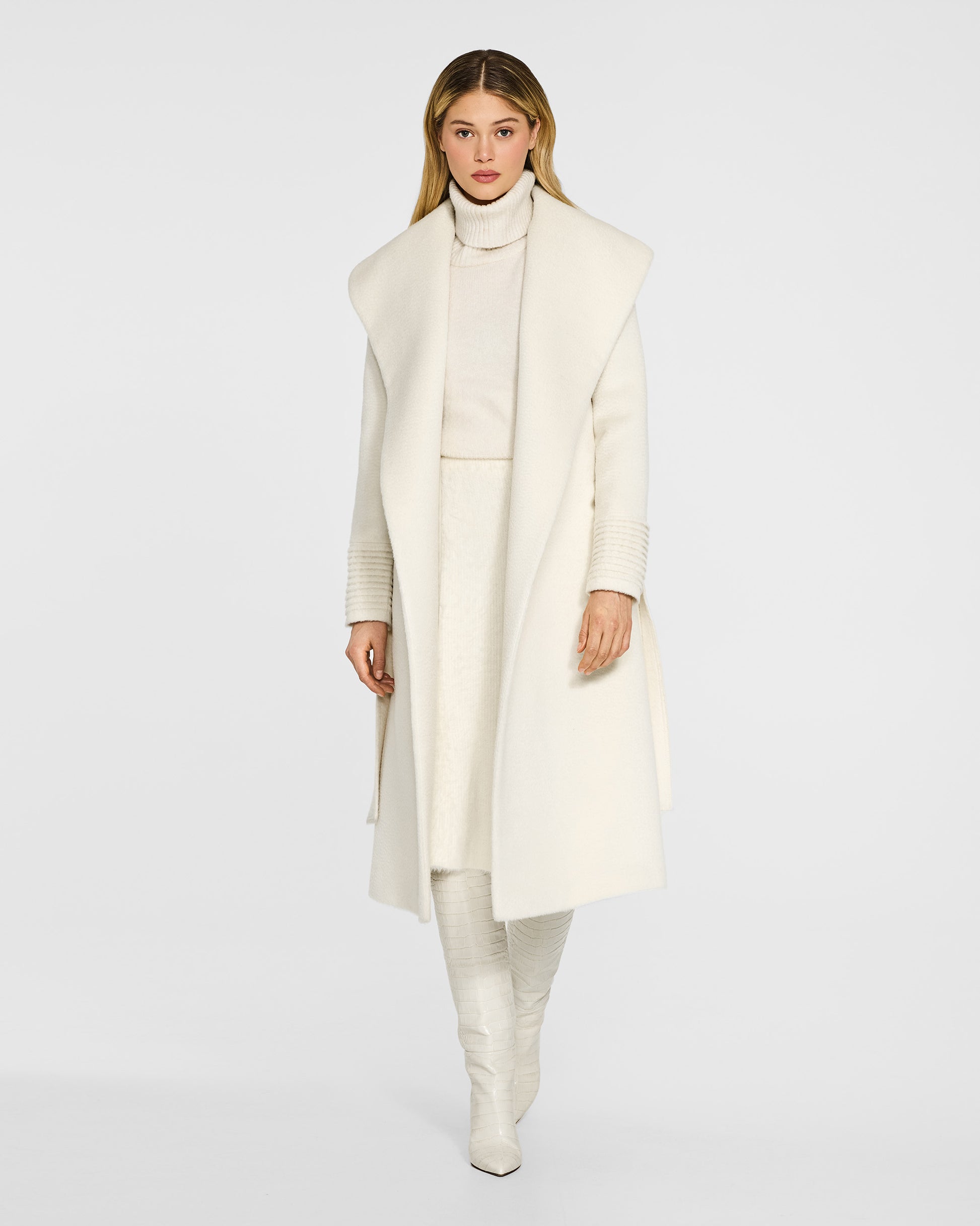 Front view of model wearing a Sentaler long ivory wrap coat made of suri alpaca wool, with a shawl collar, worn open.