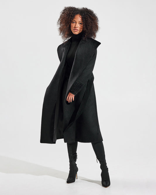 Front view of model wearing a Sentaler long black wrap coat made of suri alpaca wool, with a shawl collar, worn open.