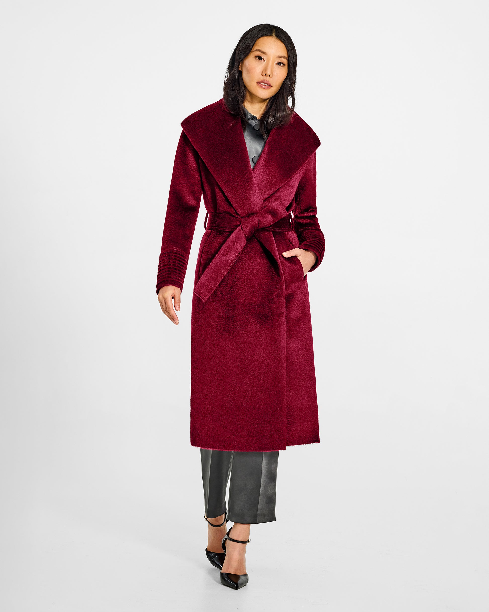 Front view of model wearing a Sentaler long bordeaux wrap coat made of suri alpaca wool, with a shawl collar, worn belted.