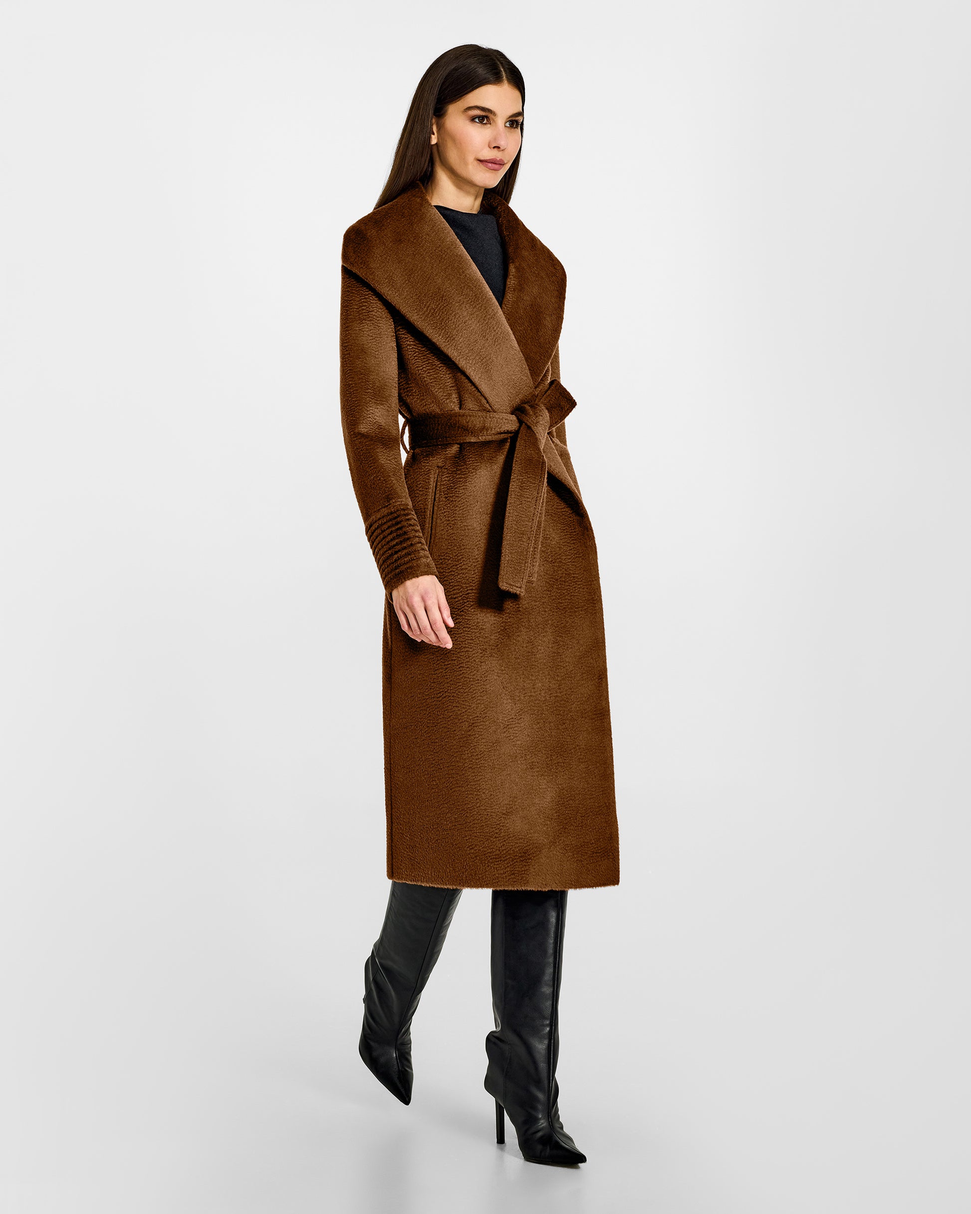 Side view of model wearing a Sentaler long caramel wrap coat made of suri alpaca wool, with a shawl collar, worn belted.