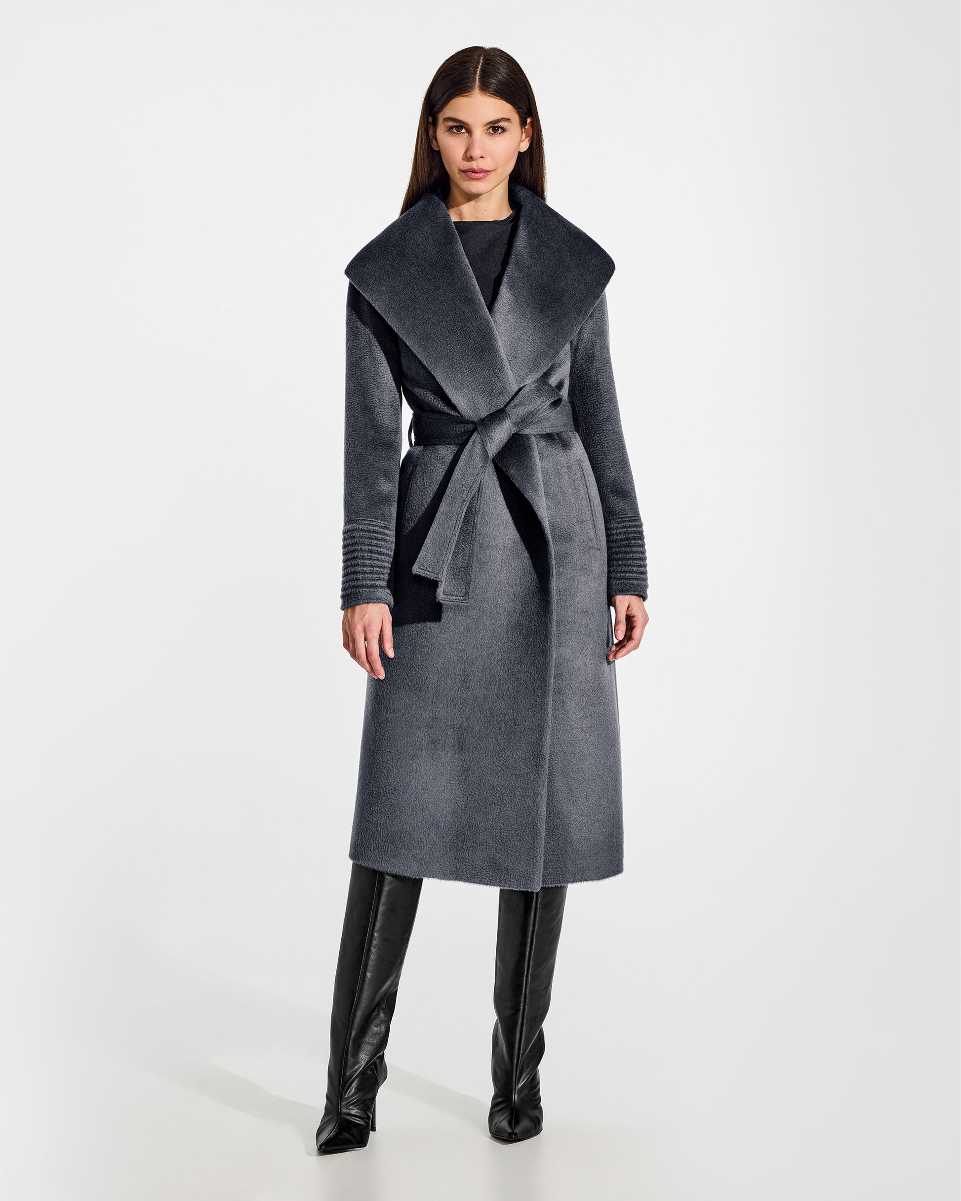 Front view of model wearing a Sentaler long graphite grey wrap coat made of suri alpaca wool, with a shawl collar, worn belted.