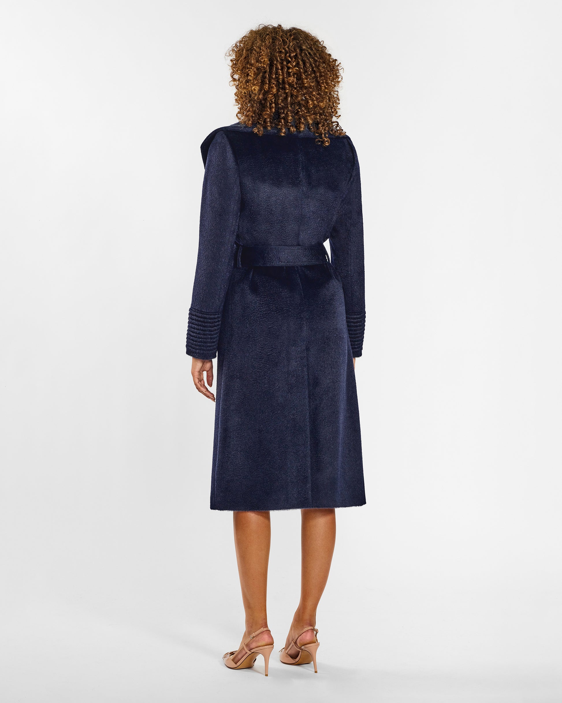 Back view of model wearing a Sentaler long deep navy wrap coat made of suri alpaca wool, with a shawl collar, worn belted.