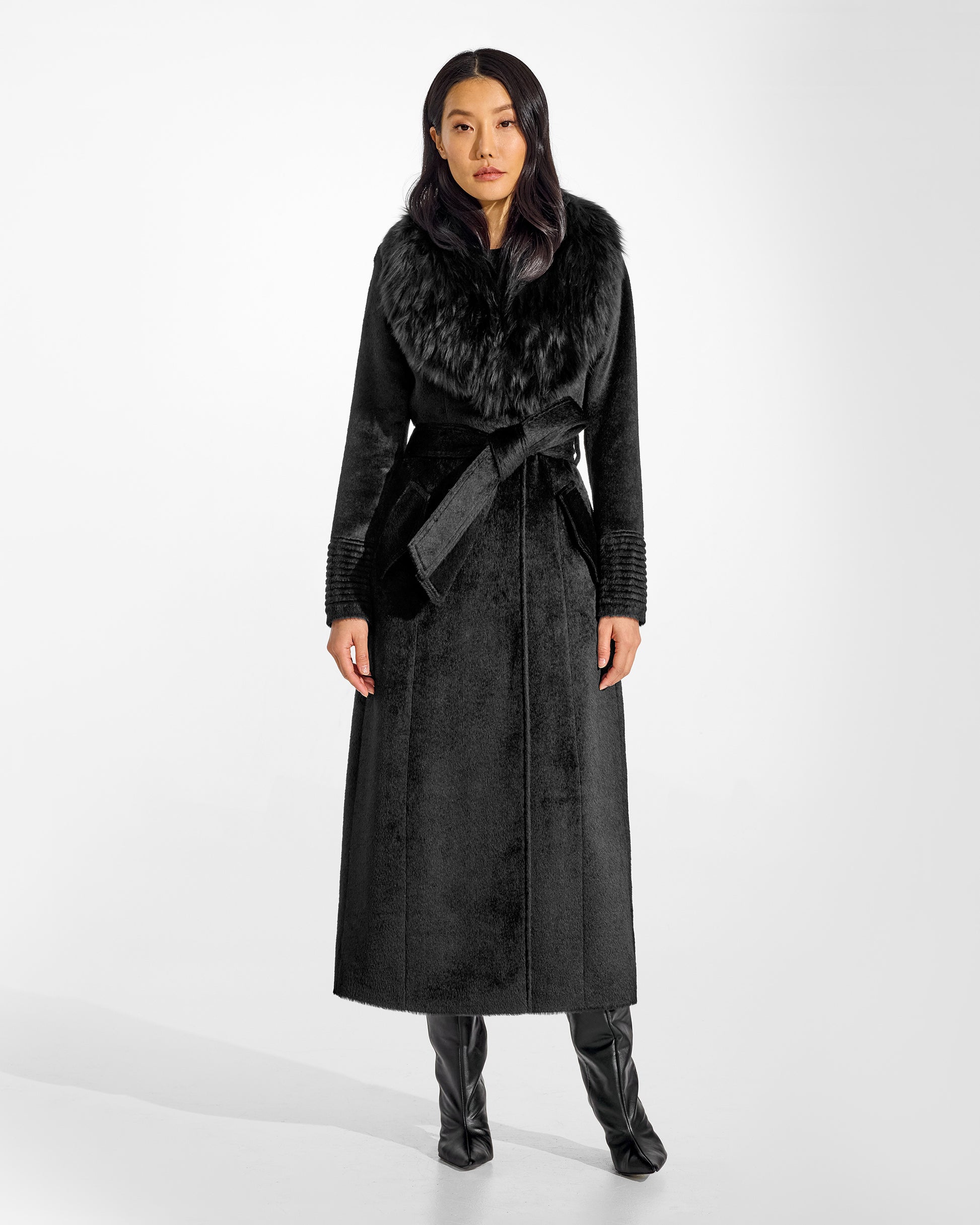 Front view of model wearing a Sentaler black maxi coat made of suri alpaca wool, with an alpaca shearling collar, seen belted.