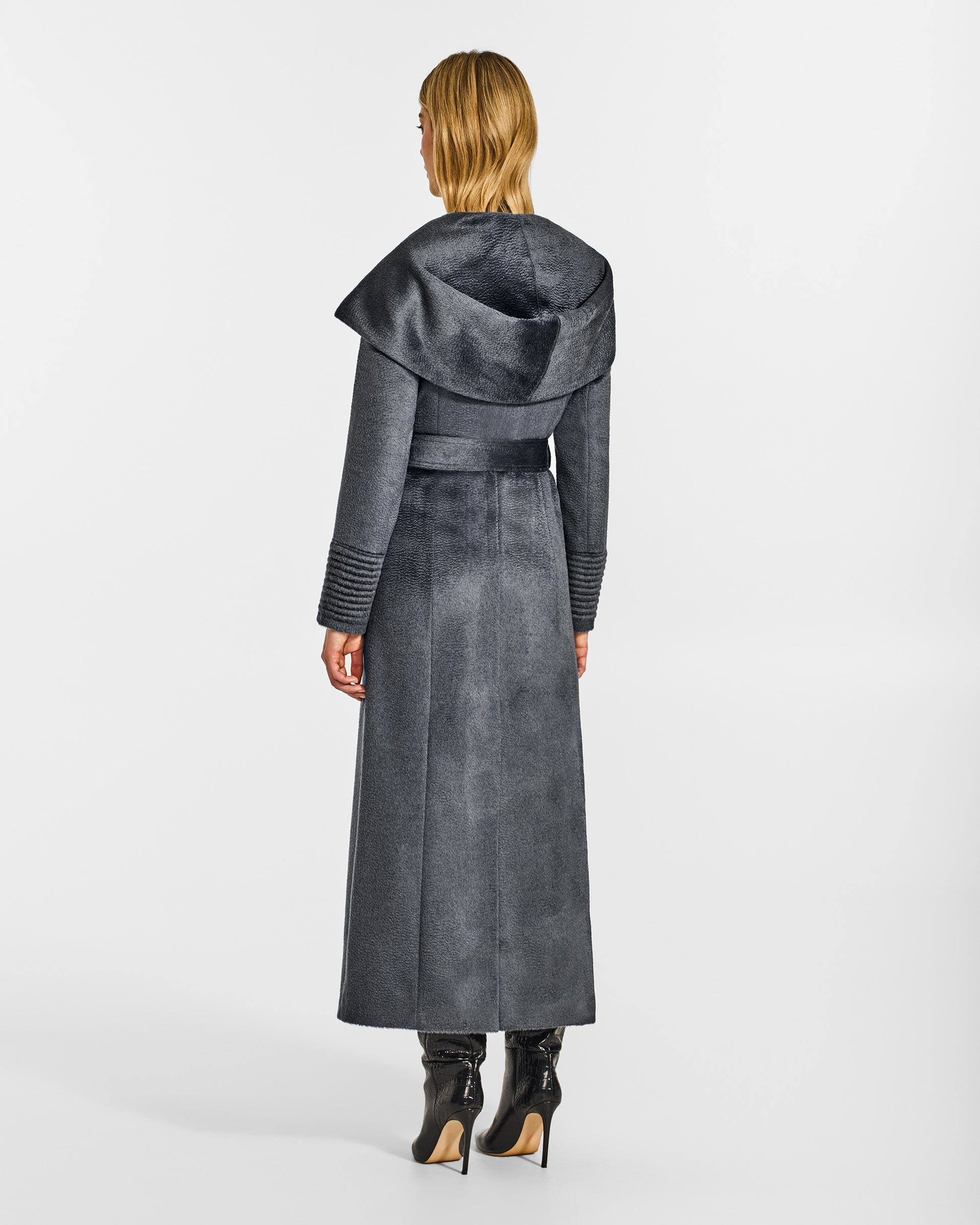 Back view of model wearing a Sentaler maxi graphite coat made of suri alpaca wool, with a hooded collar, worn belted.