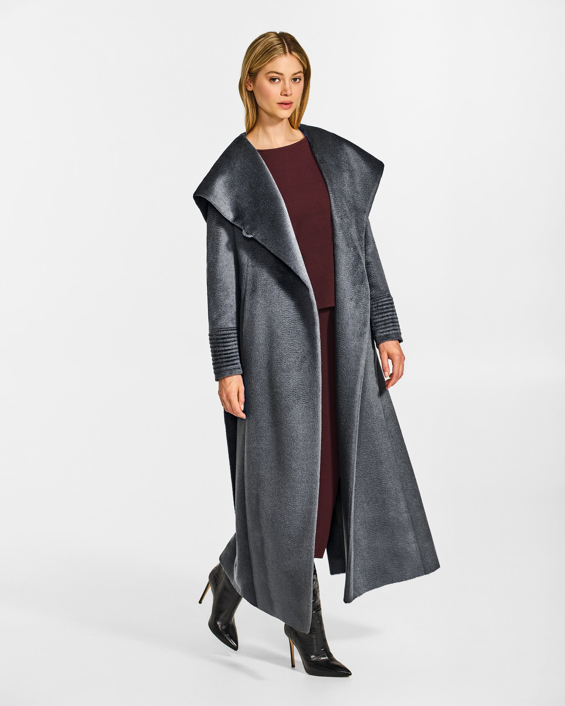Side view of model wearing a Sentaler maxi graphite coat made of suri alpaca wool, with a hooded collar, worn open.