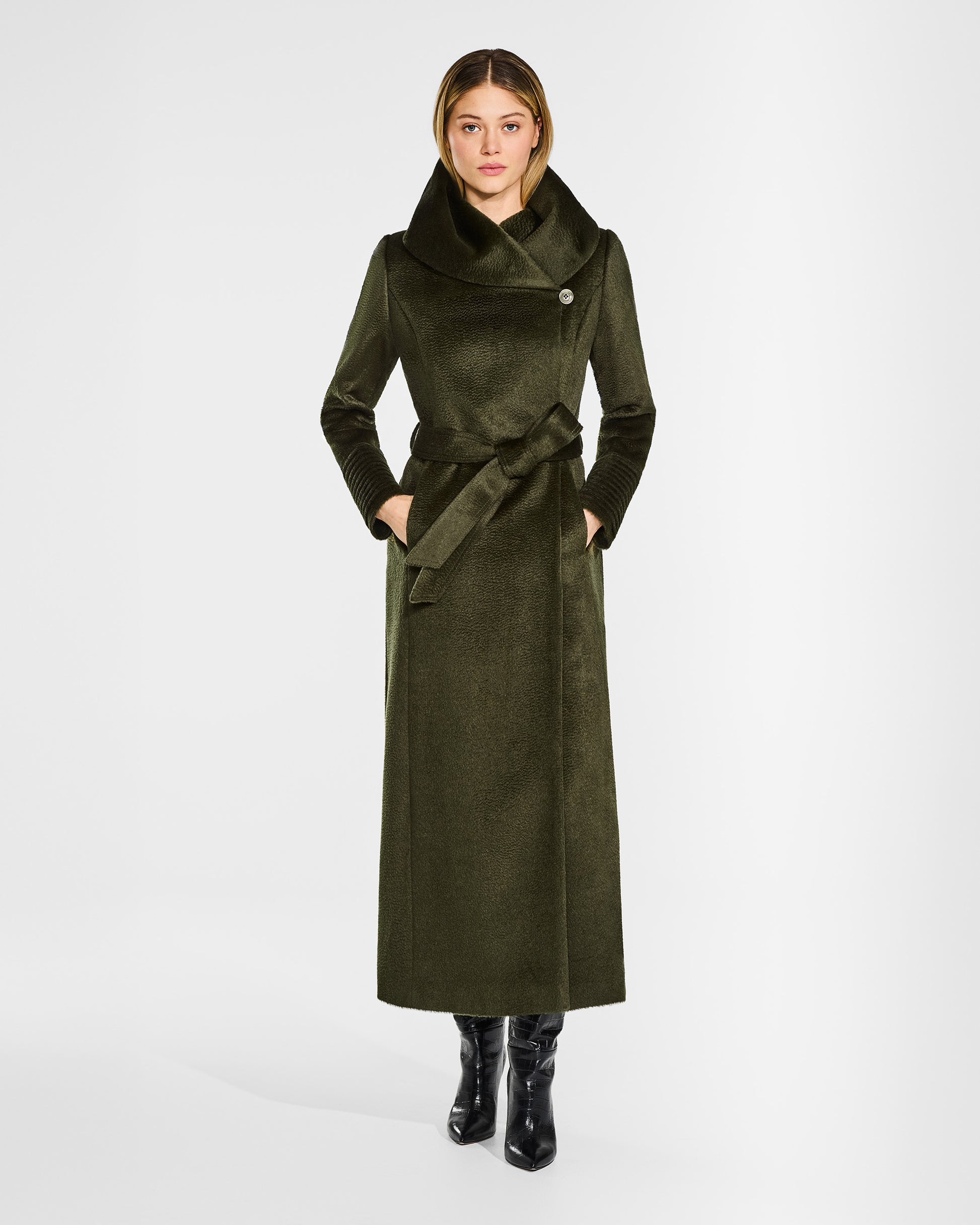 Front view of model wearing a Sentaler maxi olive green coat made of suri alpaca wool, with a hooded collar, worn buttoned and belted.