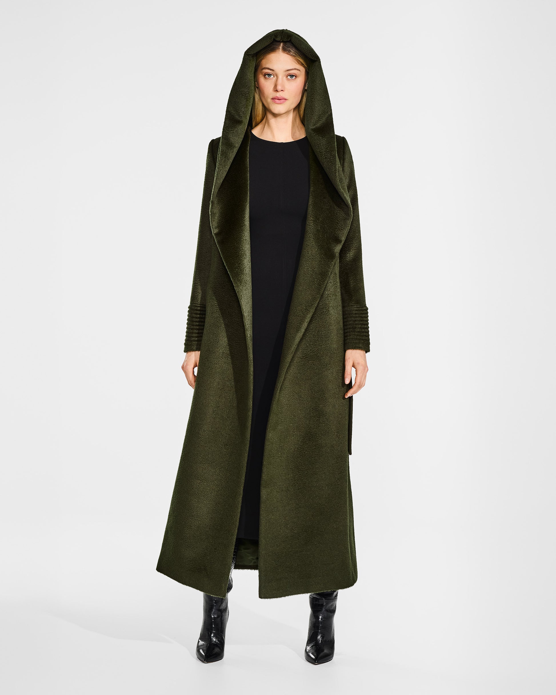 Front view of model wearing a Sentaler maxi olive green coat made of suri alpaca wool, with a hooded collar, worn open with hood.
