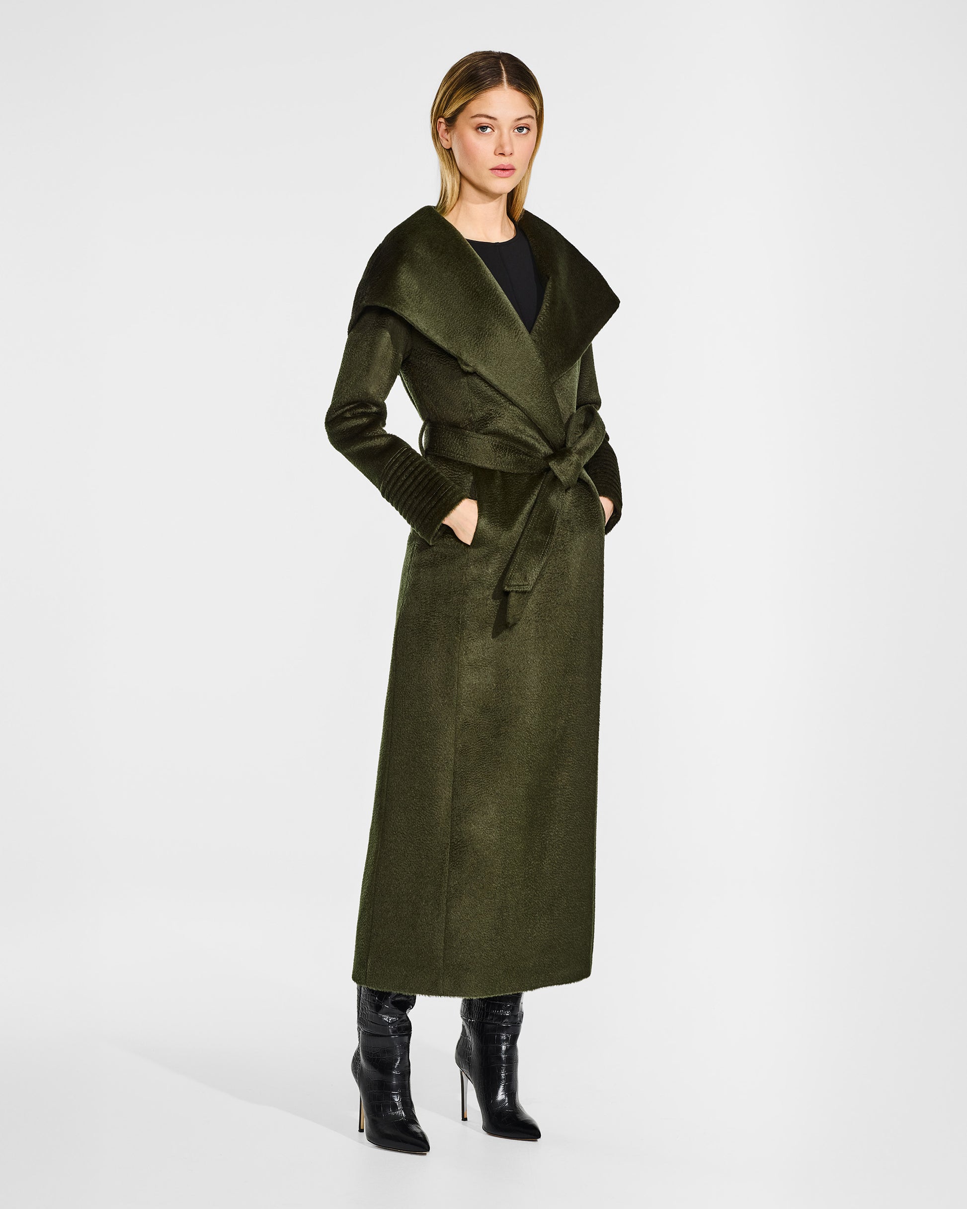 Side view of model wearing a Sentaler maxi olive green coat made of suri alpaca wool, with a hooded collar, worn belted with shawl collar.