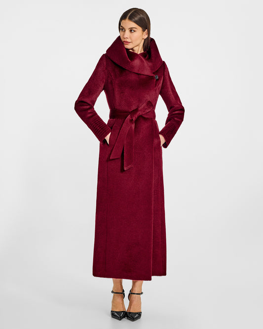 Front view of model wearing a Sentaler maxi bordeaux coat made of suri alpaca wool, with a hooded collar, worn belted.