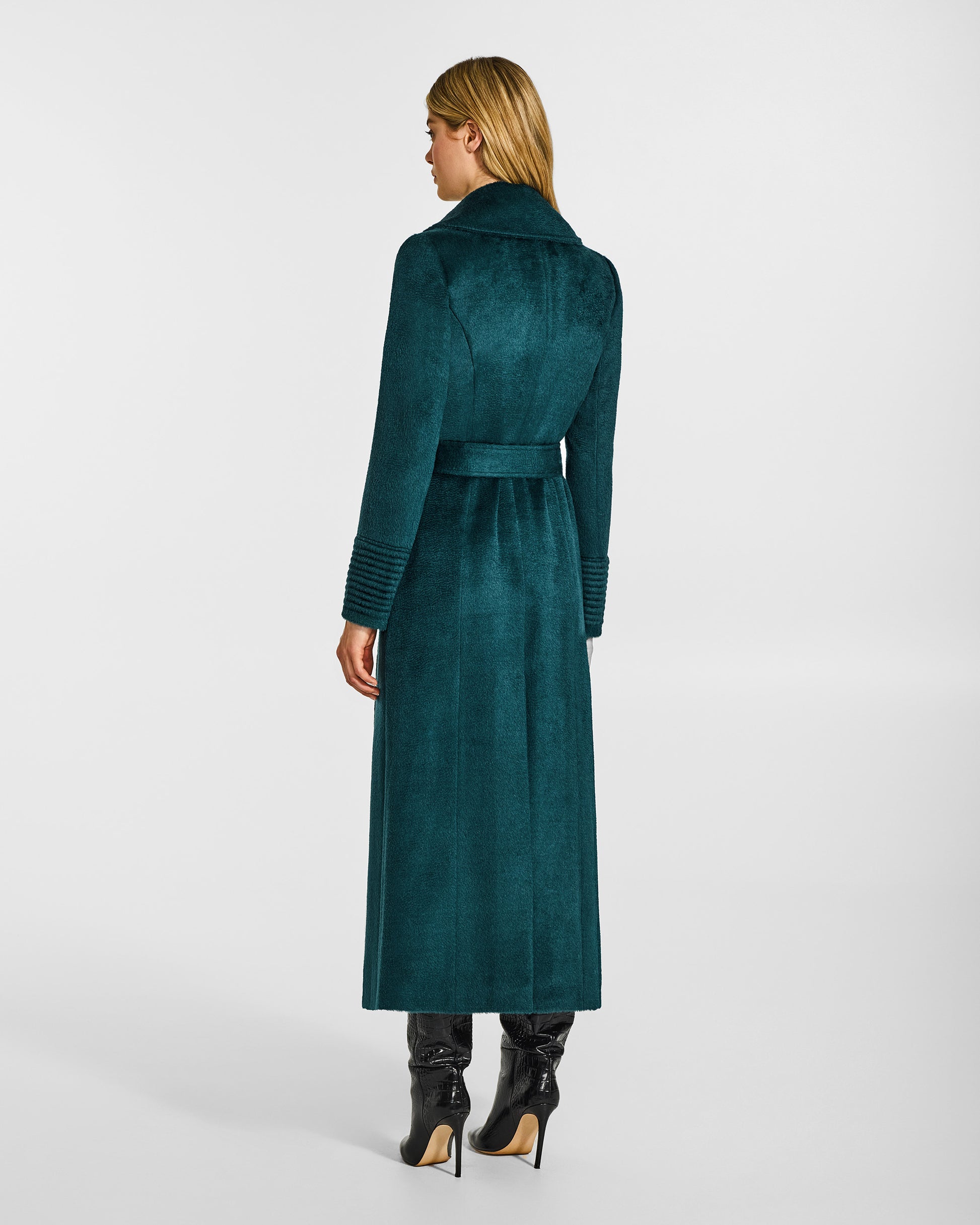Back view of model wearing a Sentaler emerald green maxi coat made of suri alpaca wool, with a notched collar, worn belted.