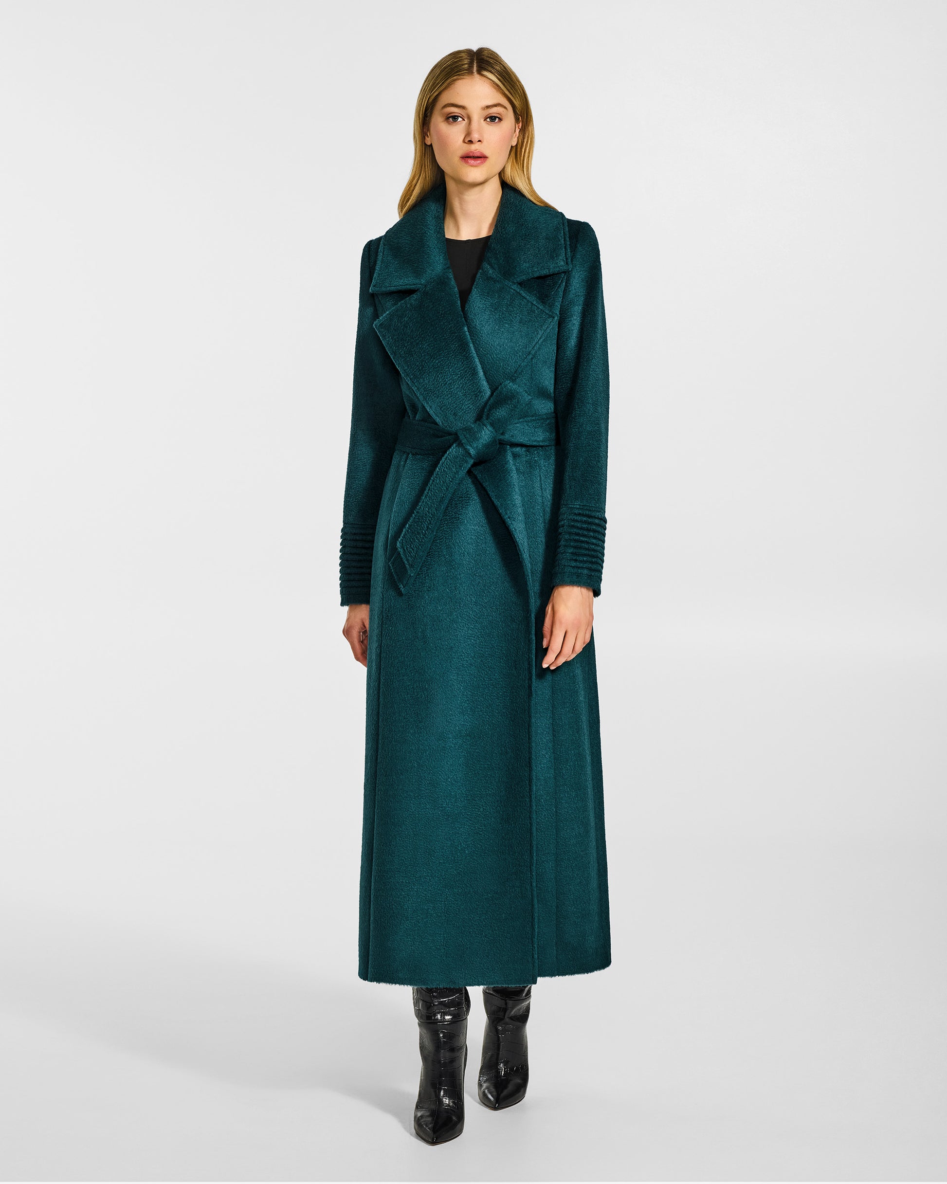 Front view of model wearing a Sentaler emerald green maxi coat made of suri alpaca wool, with a notched collar, worn belted.