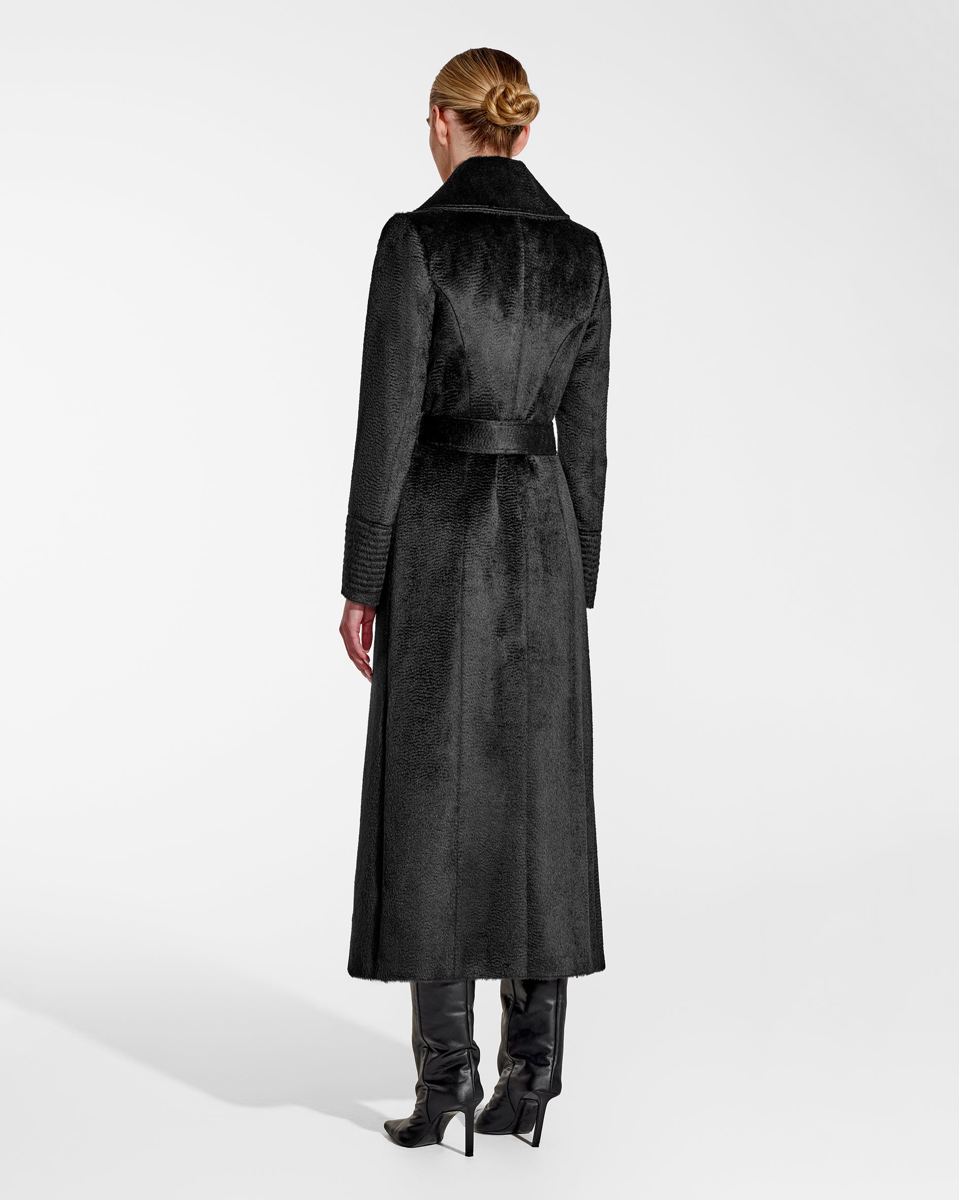 Back view of model wearing a Sentaler black maxi coat made of suri alpaca wool, with a notched collar, worn belted.